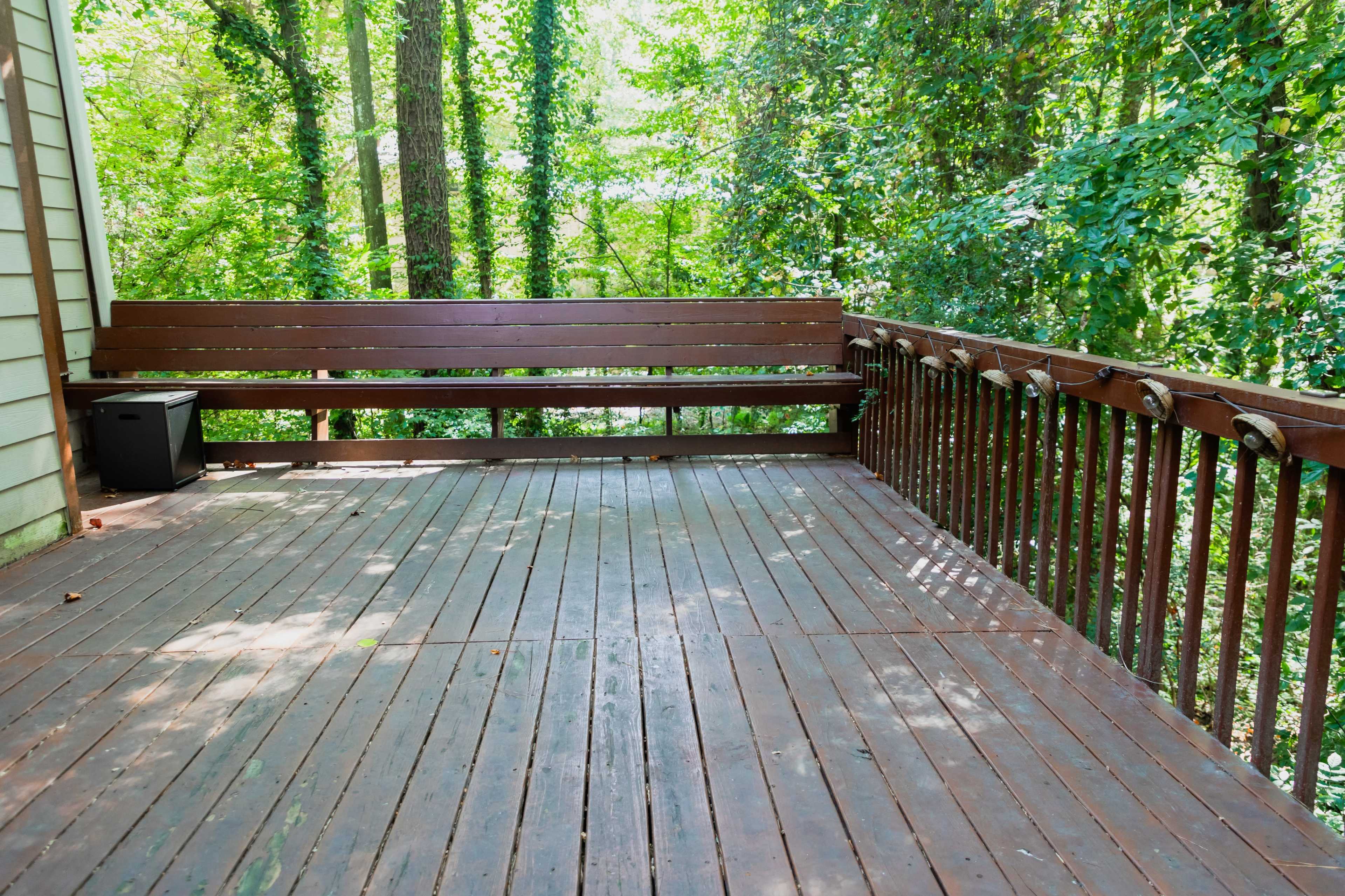 A wooden deck is surrounded by lush green trees in a forested area.