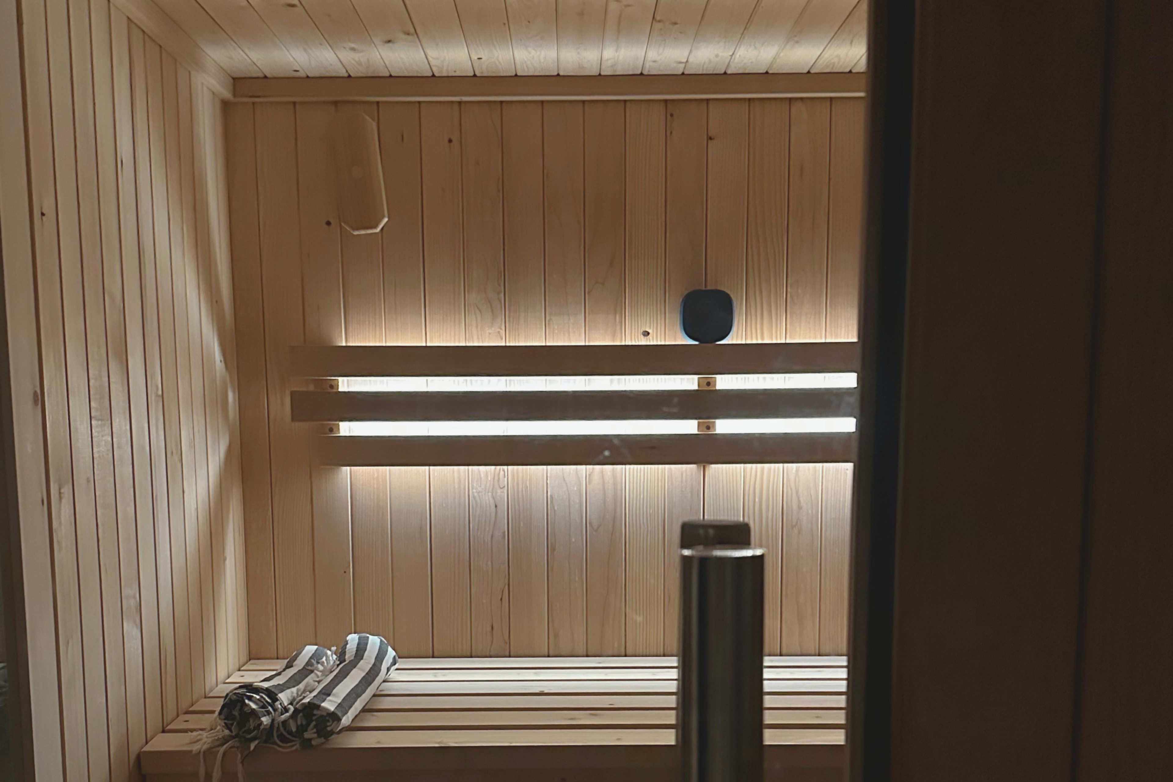 The interior of a wooden sauna with benches and a small light source.