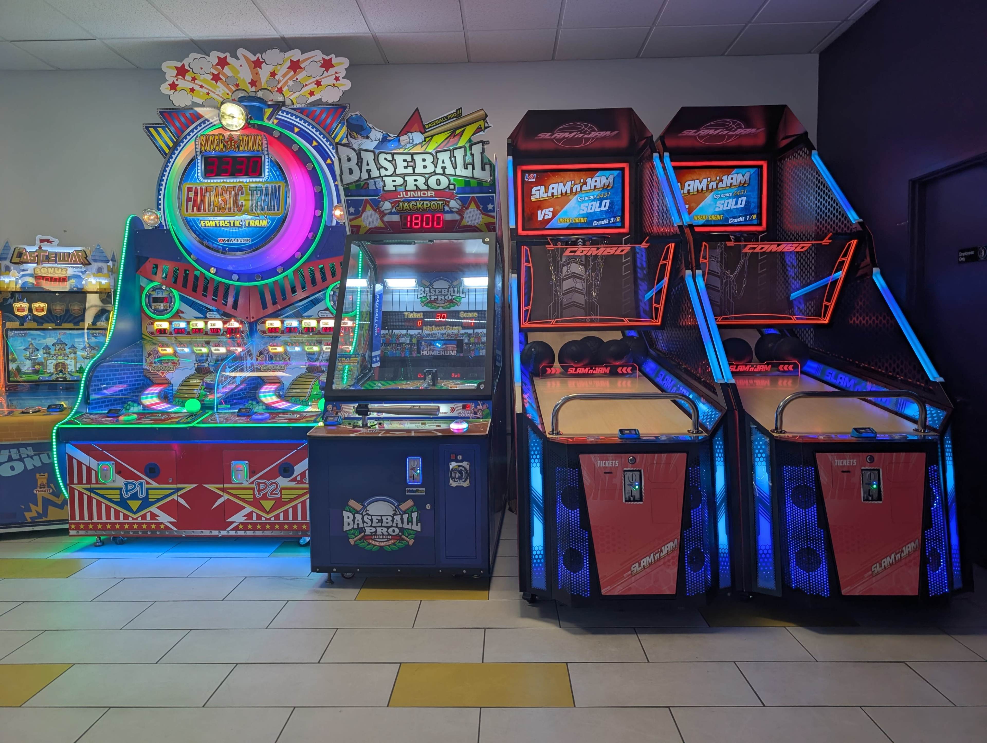 The image shows an arcade featuring a Fantasy Basketball game, a Baseball Pro game, and two Slam-A-Winner basketball machines with vibrant lighting.