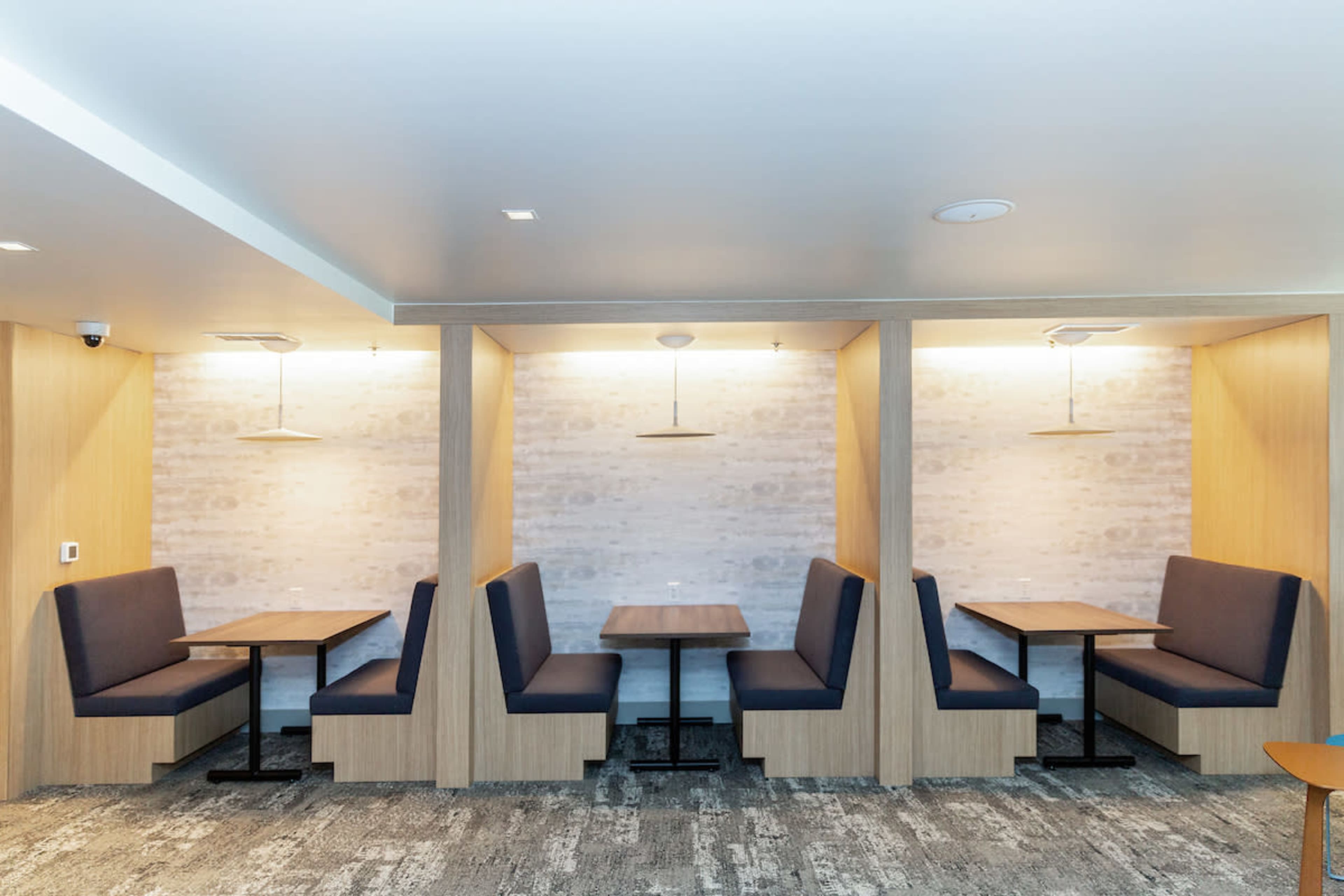 A series of booth seating areas with wooden tables and light-colored walls in a modern interior.