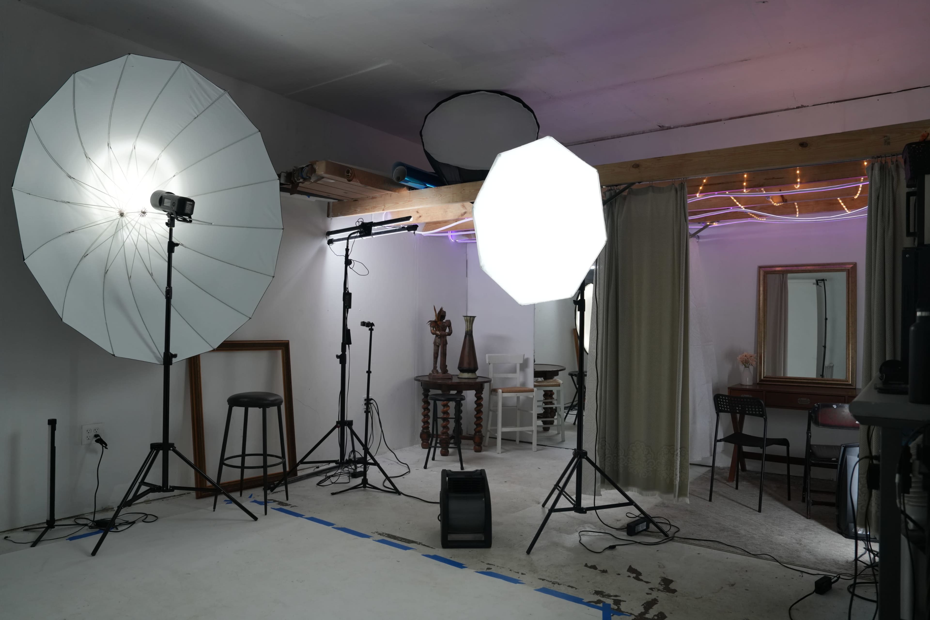 A photography studio equipped with softbox lights, a stool, and various props in a minimally decorated space.