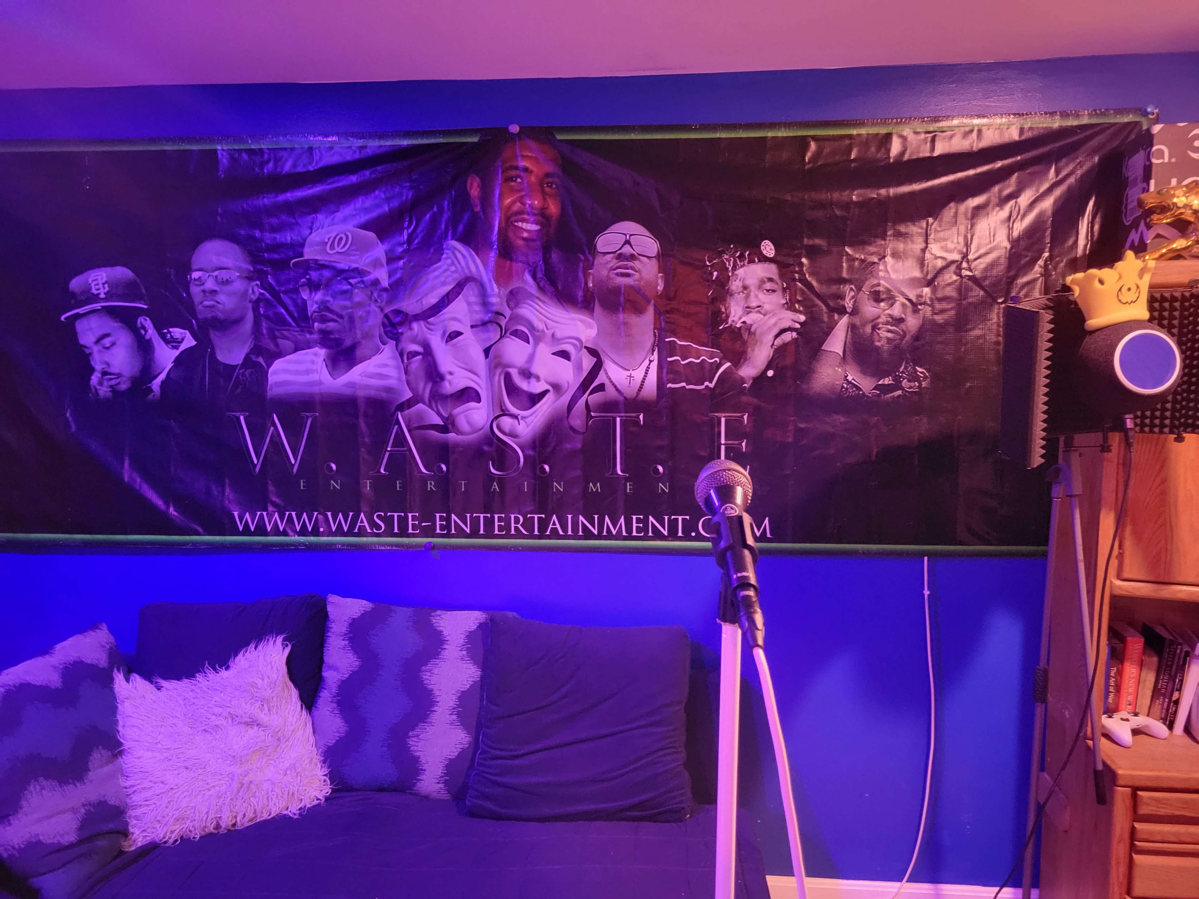 A wall with a banner featuring multiple individuals and a microphone in front of a cozy room illuminated in blue.