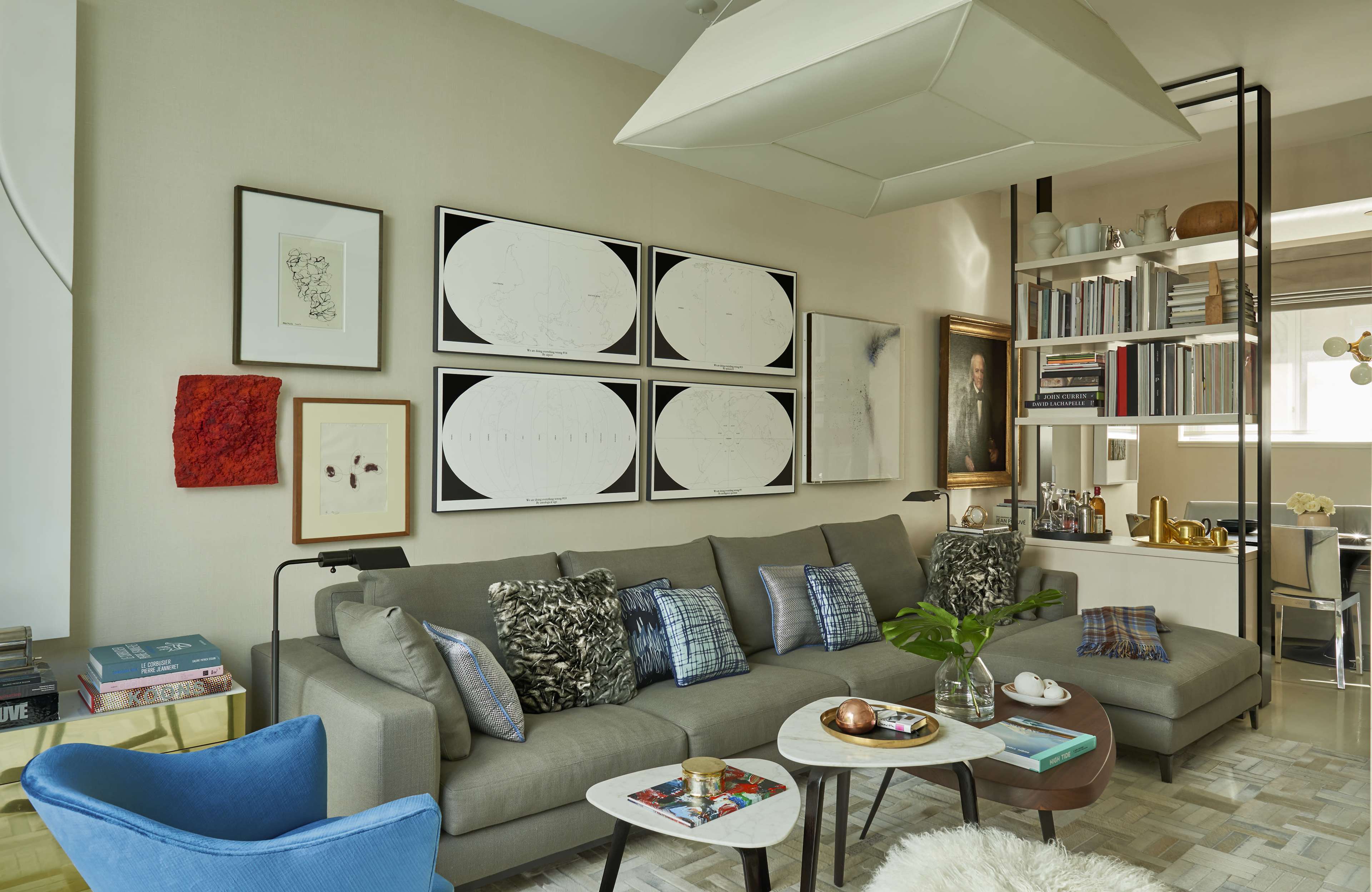 A modern living room with a gray sofa adorned with decorative pillows, two coffee tables, and a wall featuring framed artwork.