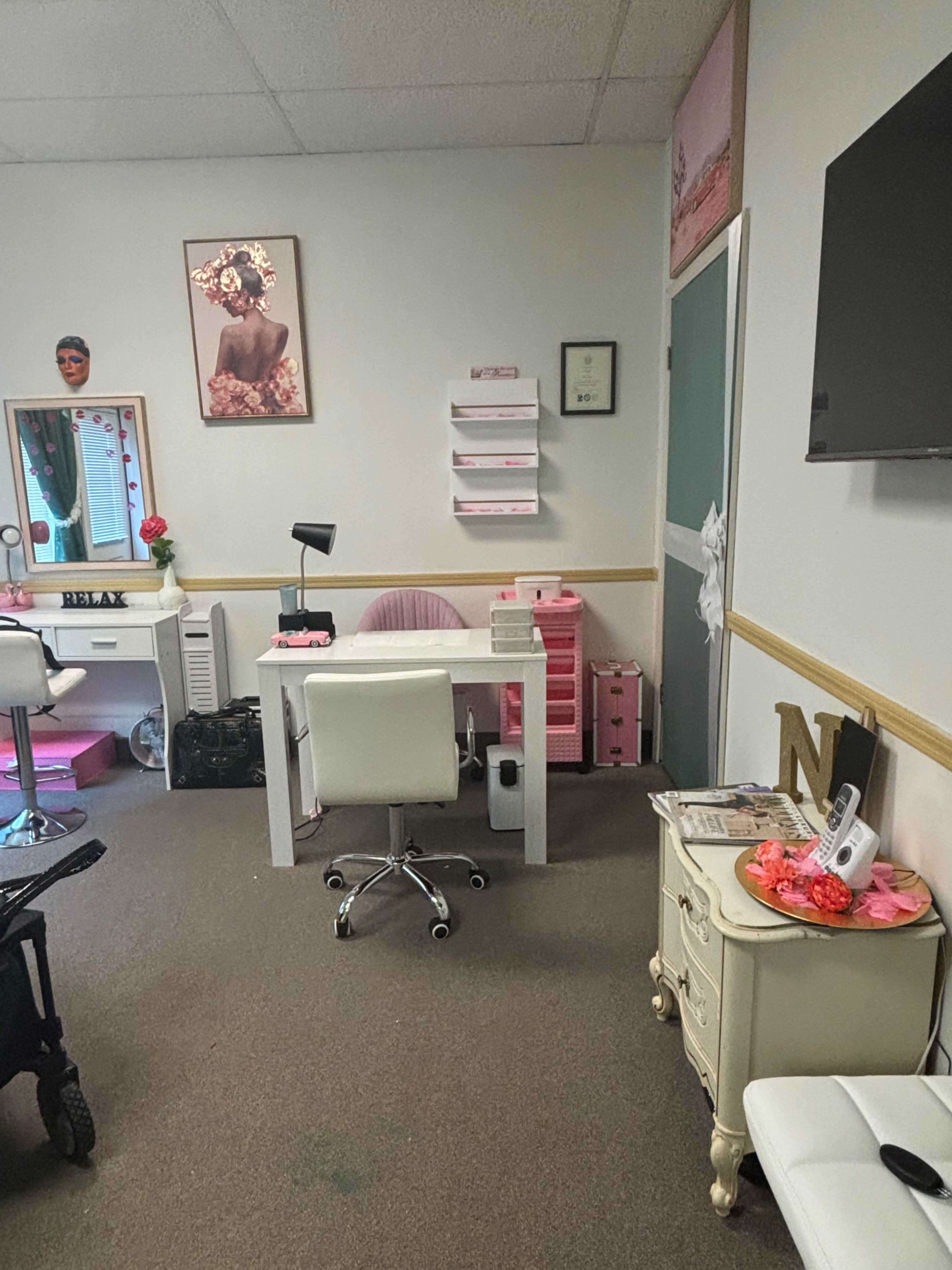 A salon or beauty studio with a white desk, a chair, storage units, and decorative elements on the walls.