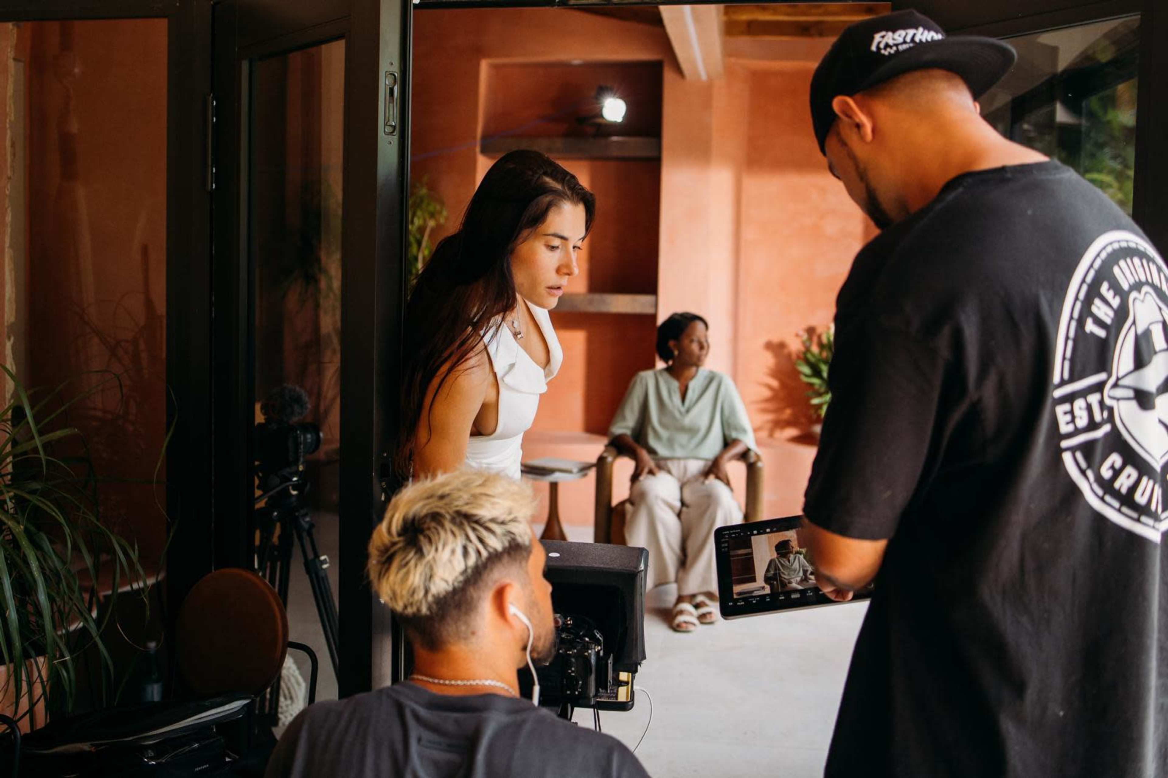 A film crew is assembling equipment while a woman sits in a chair in the background.