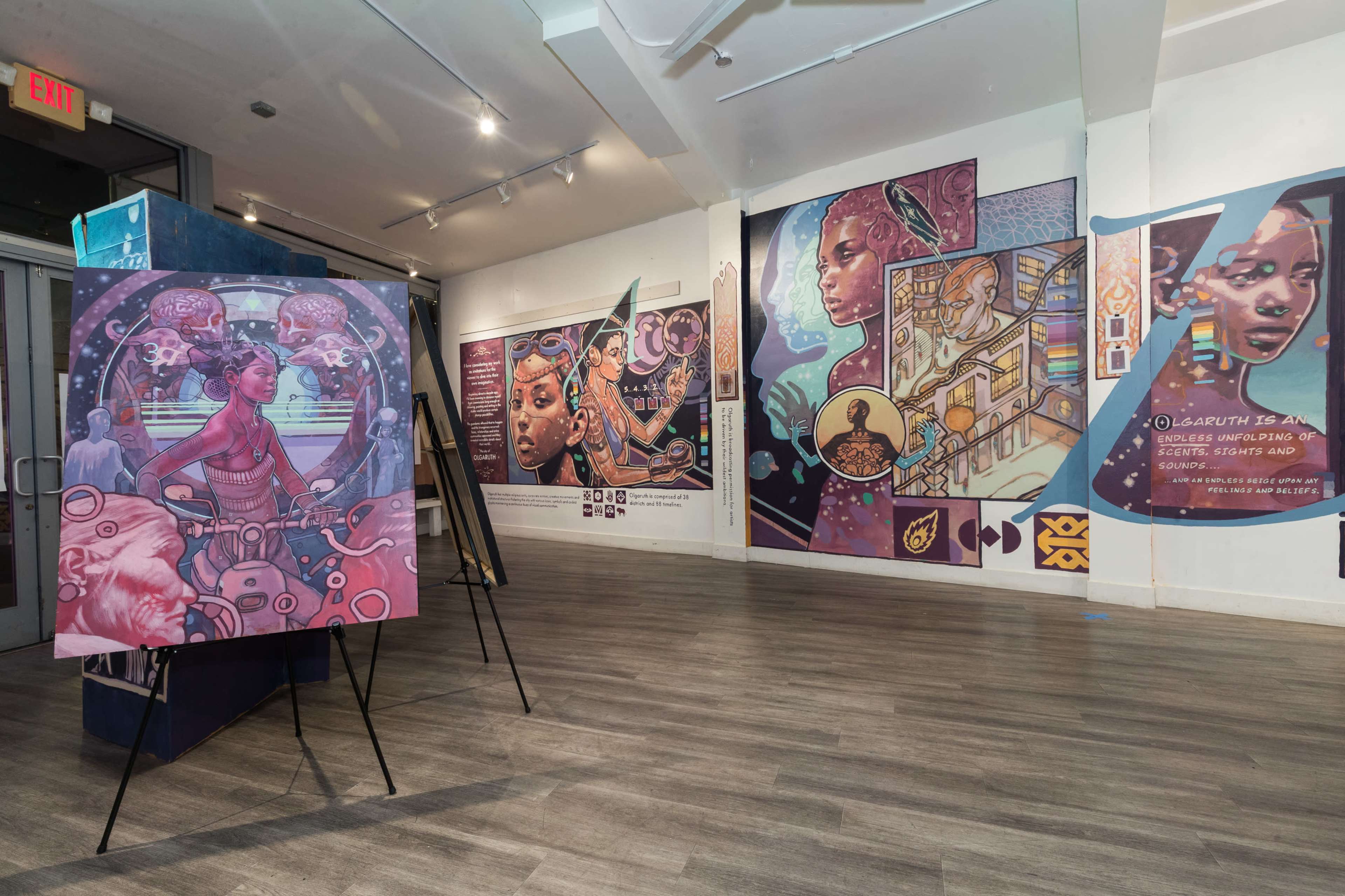 The image shows an art gallery with colorful murals and paintings displayed on the walls and easels, featuring diverse themes and characters.