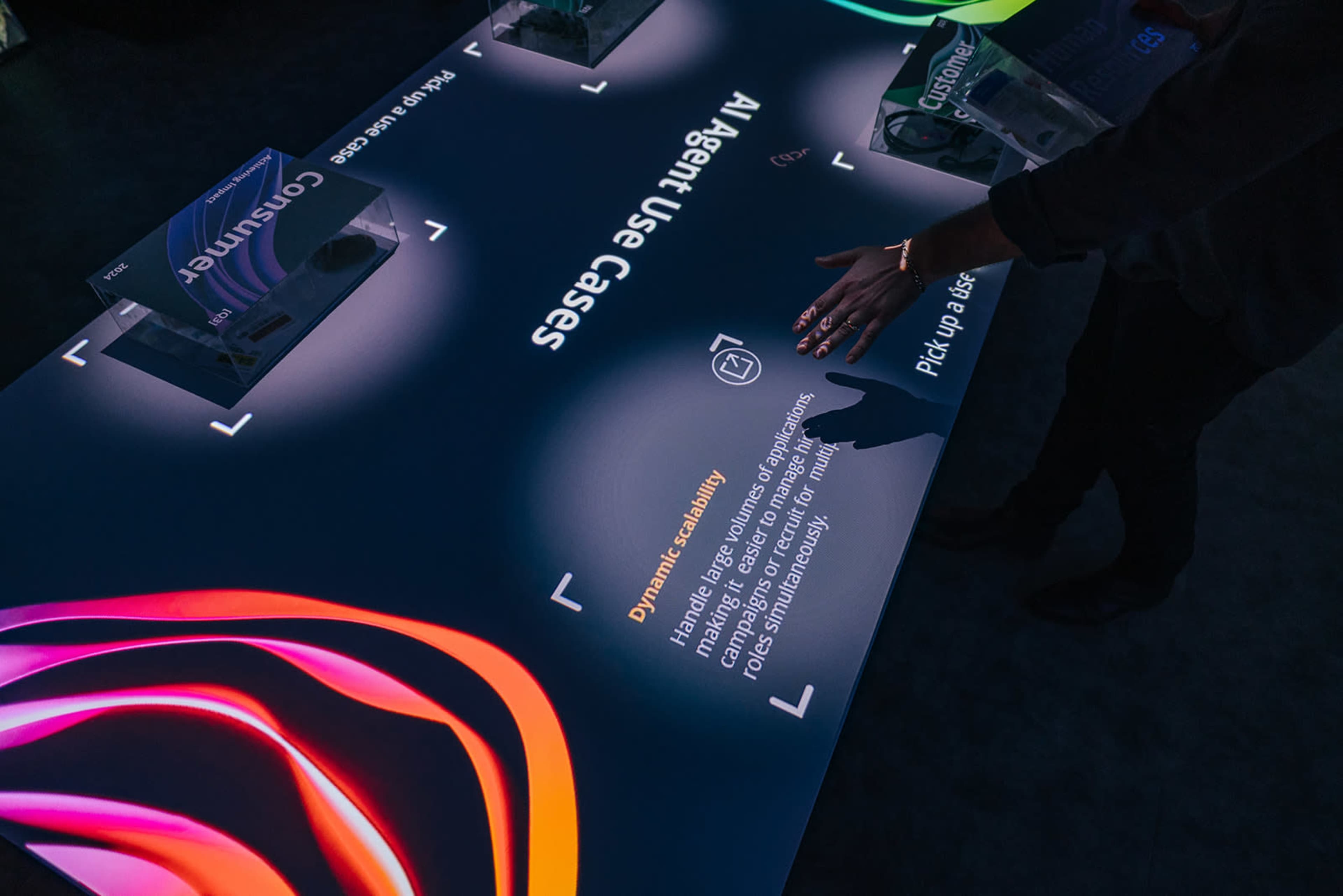 A person interacts with a large, illuminated touchscreen display featuring information on AI applications and user cases.