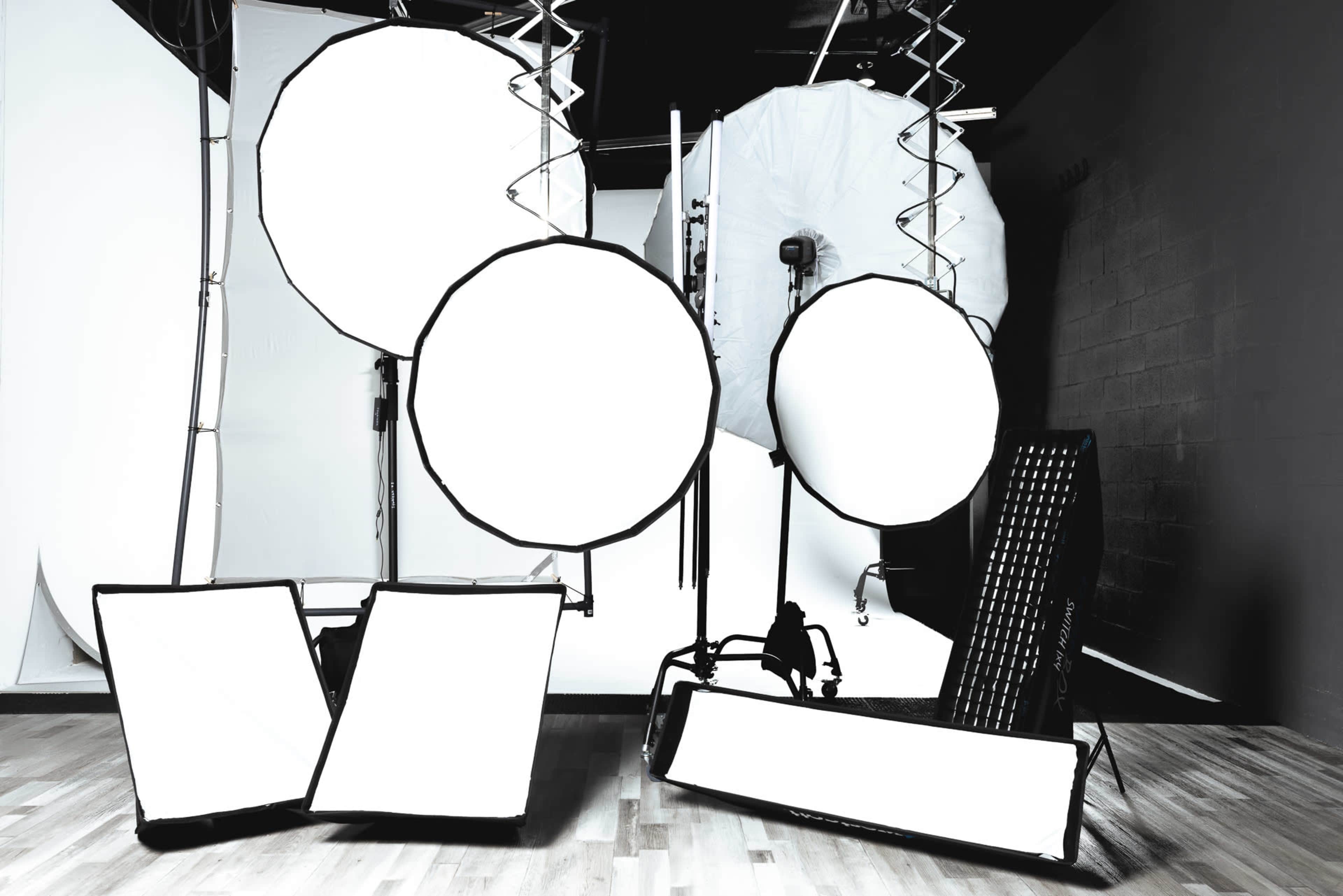 The image shows various photography lighting equipment arranged in a studio setting.