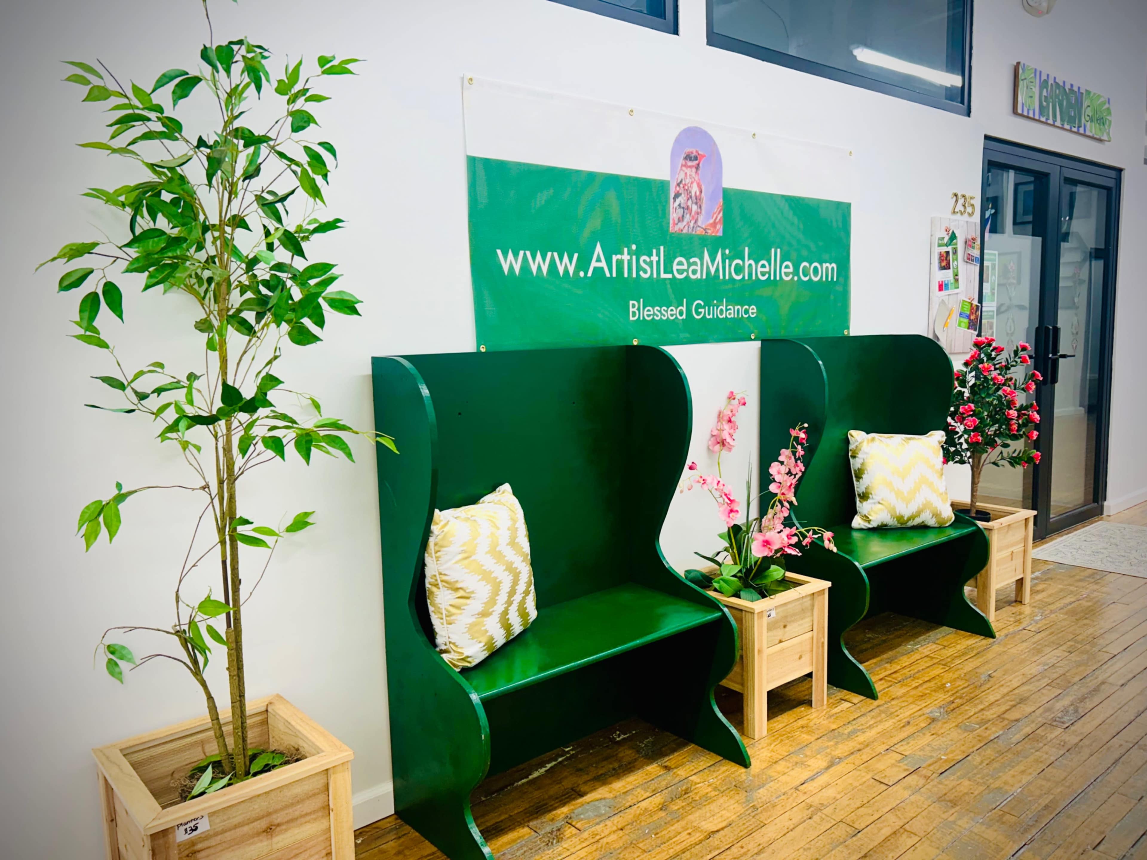 The image shows two green seating areas with decorative pillows, flanked by potted plants, and a banner above them displaying a website address and the text "Blessed Guidance."