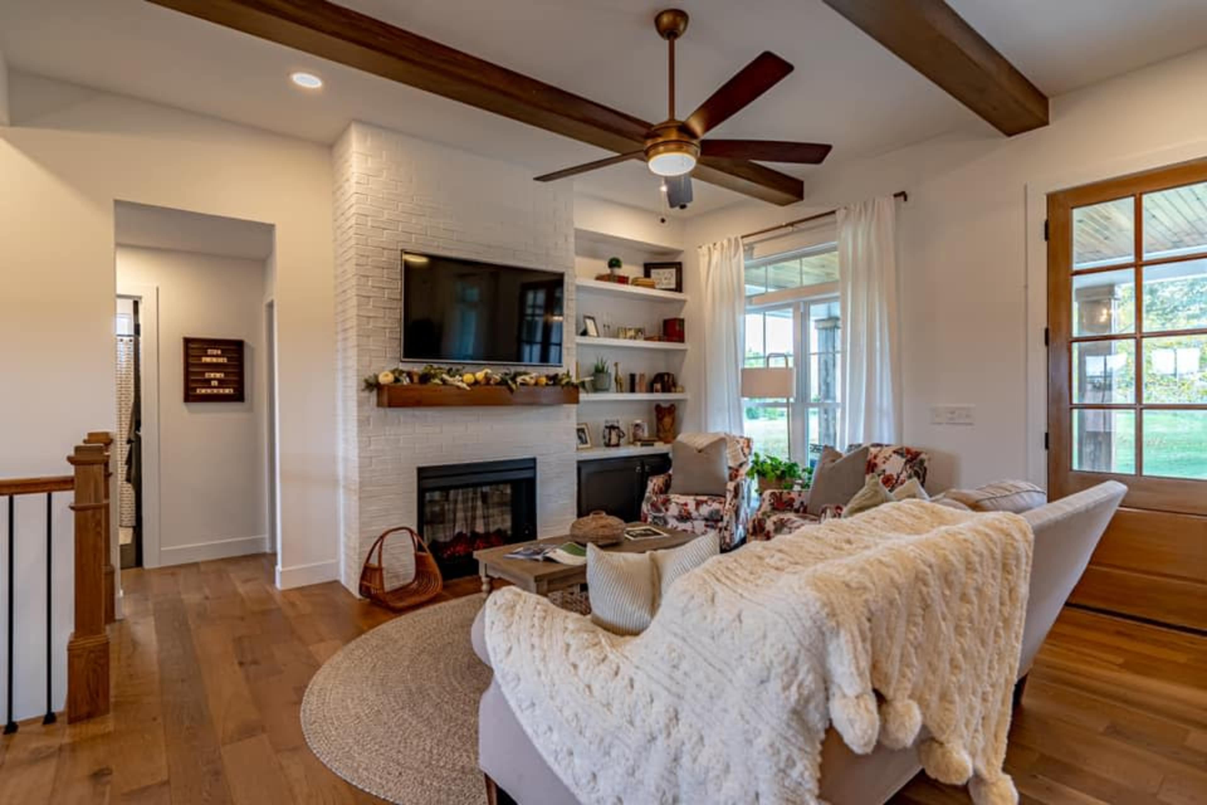 A cozy living room features a fireplace, a mounted television, and a comfortable seating area with a knit throw blanket.
