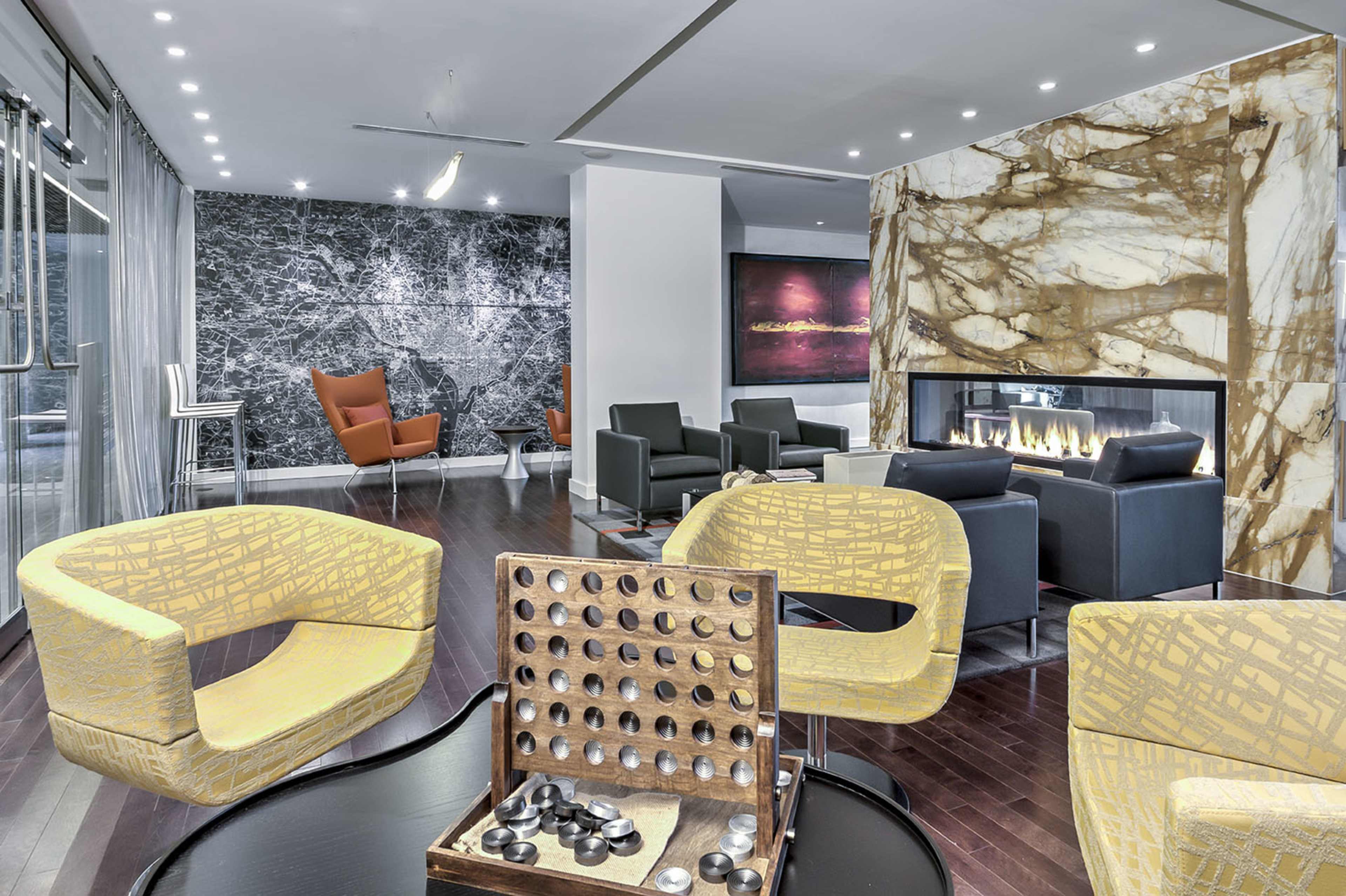 A modern lounge area featuring stylish seating, a decorative fireplace, and a checkers board on a table.