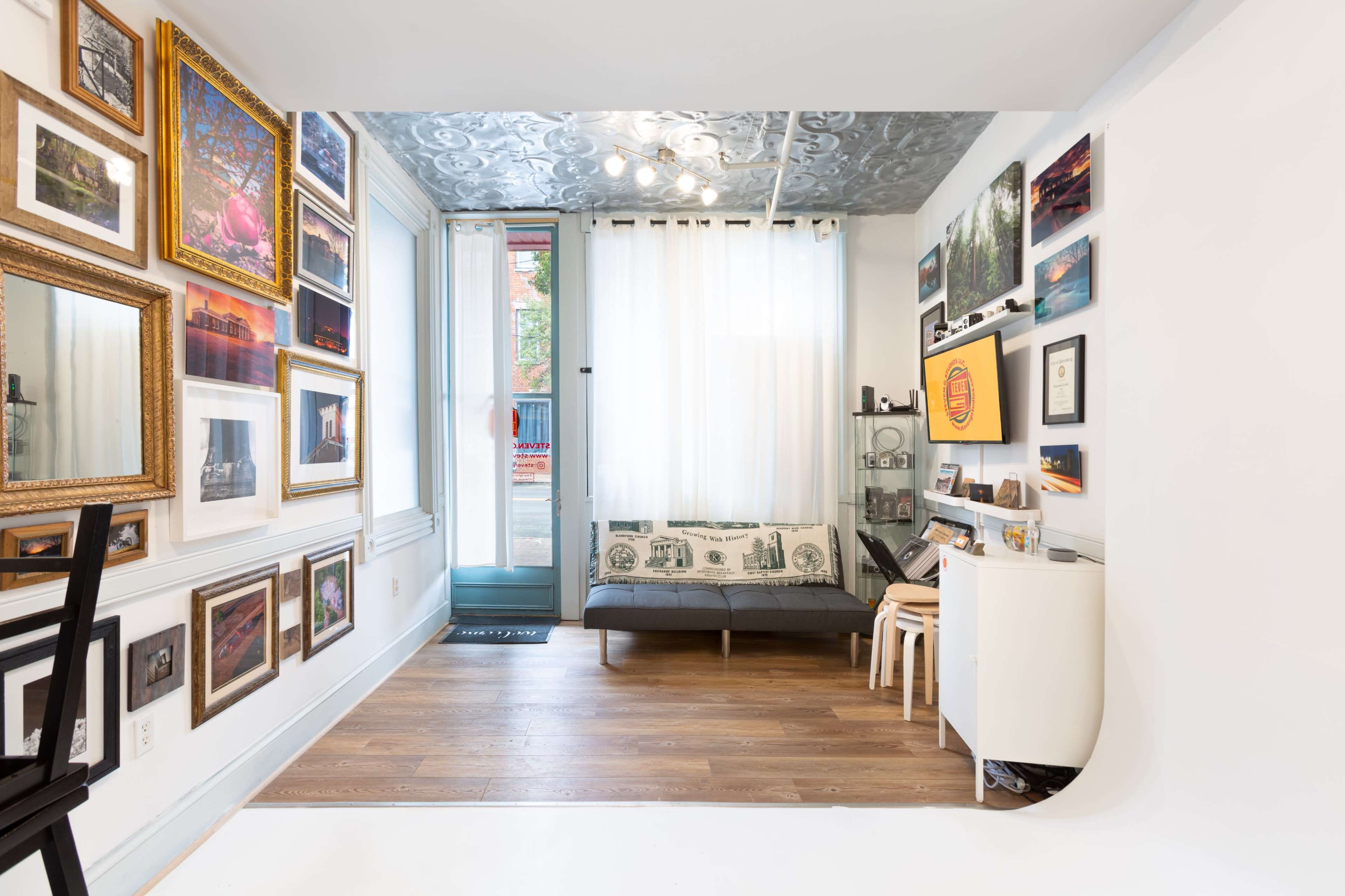 A well-decorated room features a gallery wall of framed artwork opposite a minimalist seating area with a couch and a coffee table.