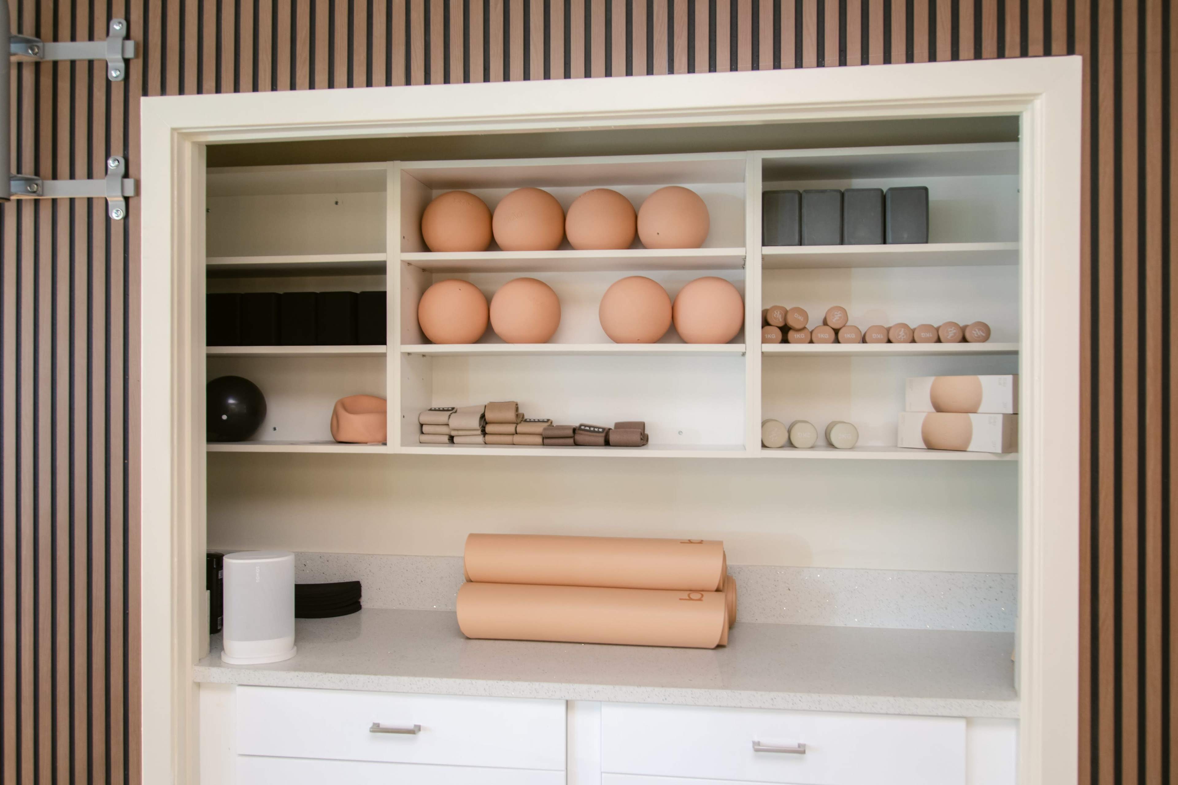 A neatly organized shelf displays various geometric shapes and materials, including spheres, blocks, and rolls in neutral tones.