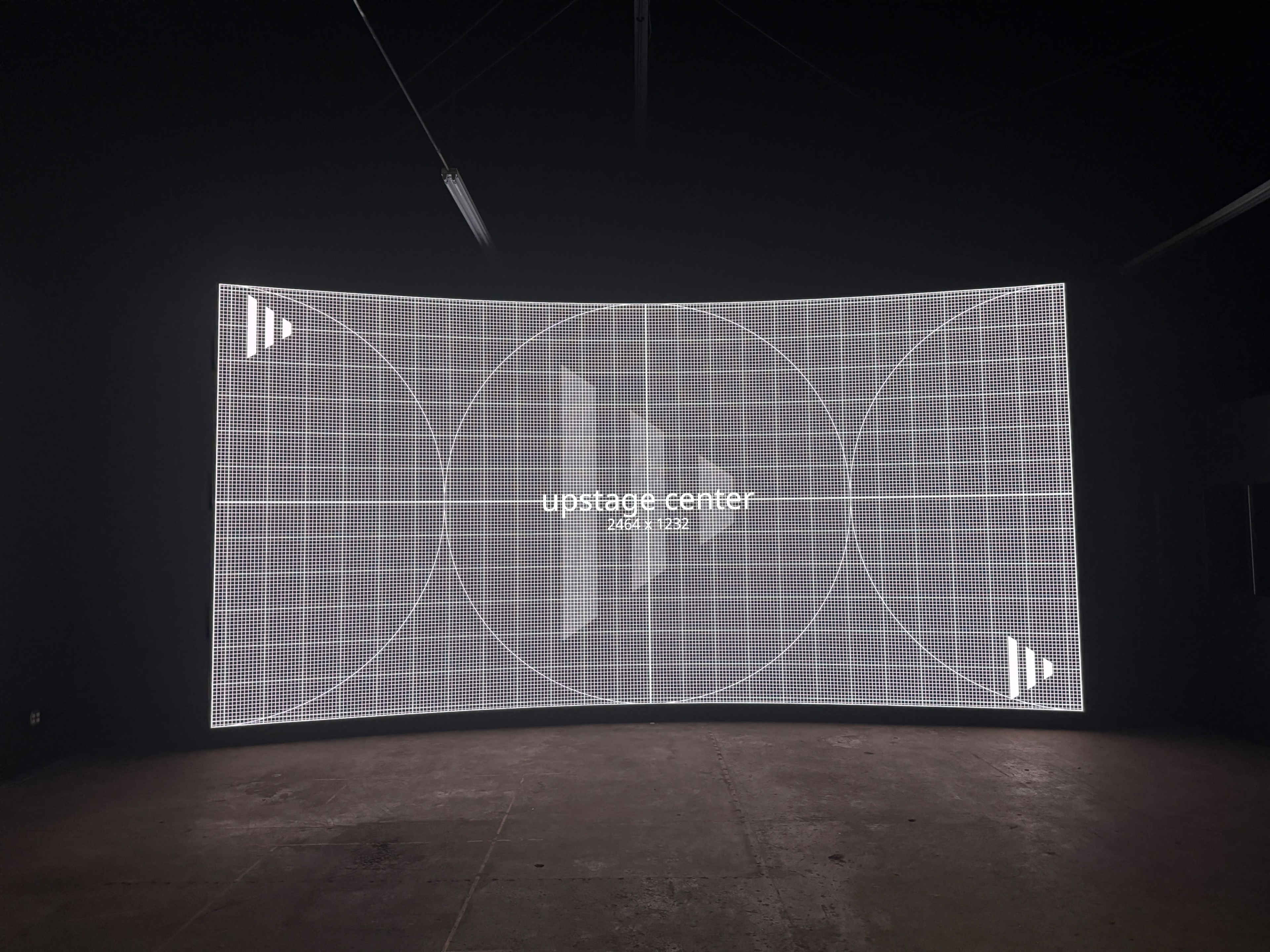 A large, curved digital screen displaying a grid pattern with the text "upstage center" in the center.