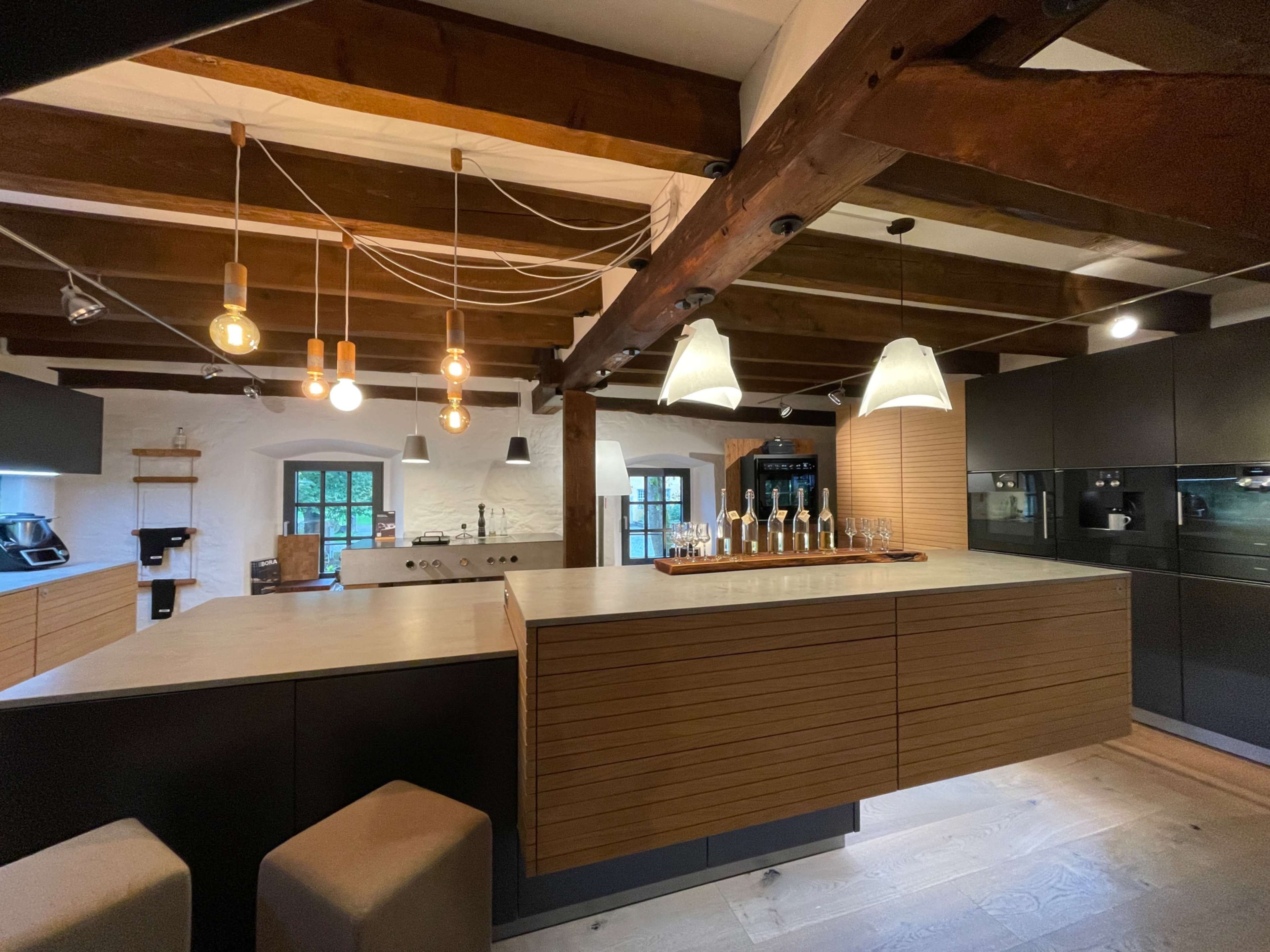 The kitchen features wooden beams, modern cabinetry, and an island with bar seating, illuminated by pendant lights.