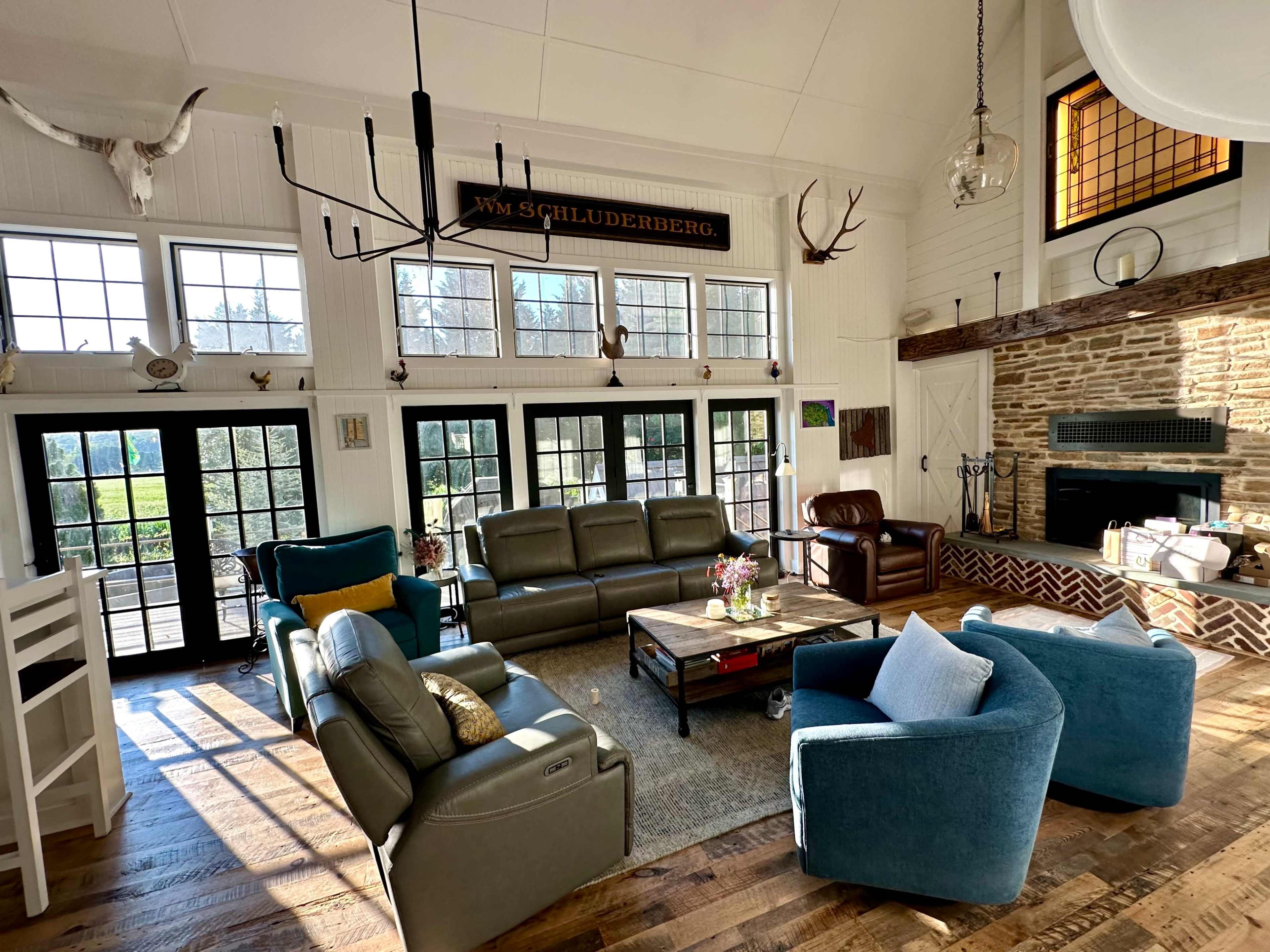 The living room features a mix of comfortable seating, a stone fireplace, and large windows that allow natural light to fill the space.