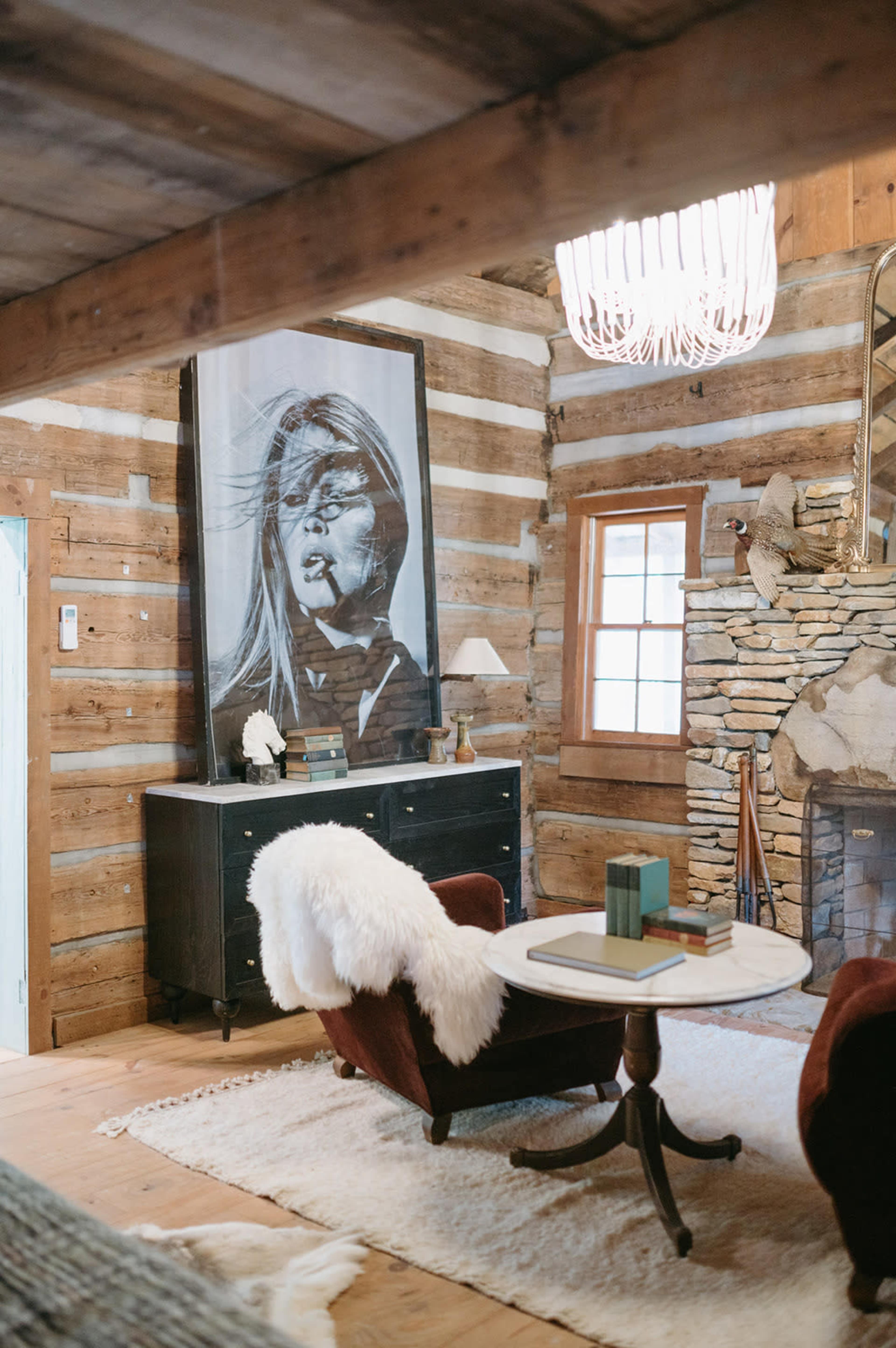 A cozy living room features a large black-and-white portrait on a wooden wall, accompanied by a round coffee table and two upholstered chairs.