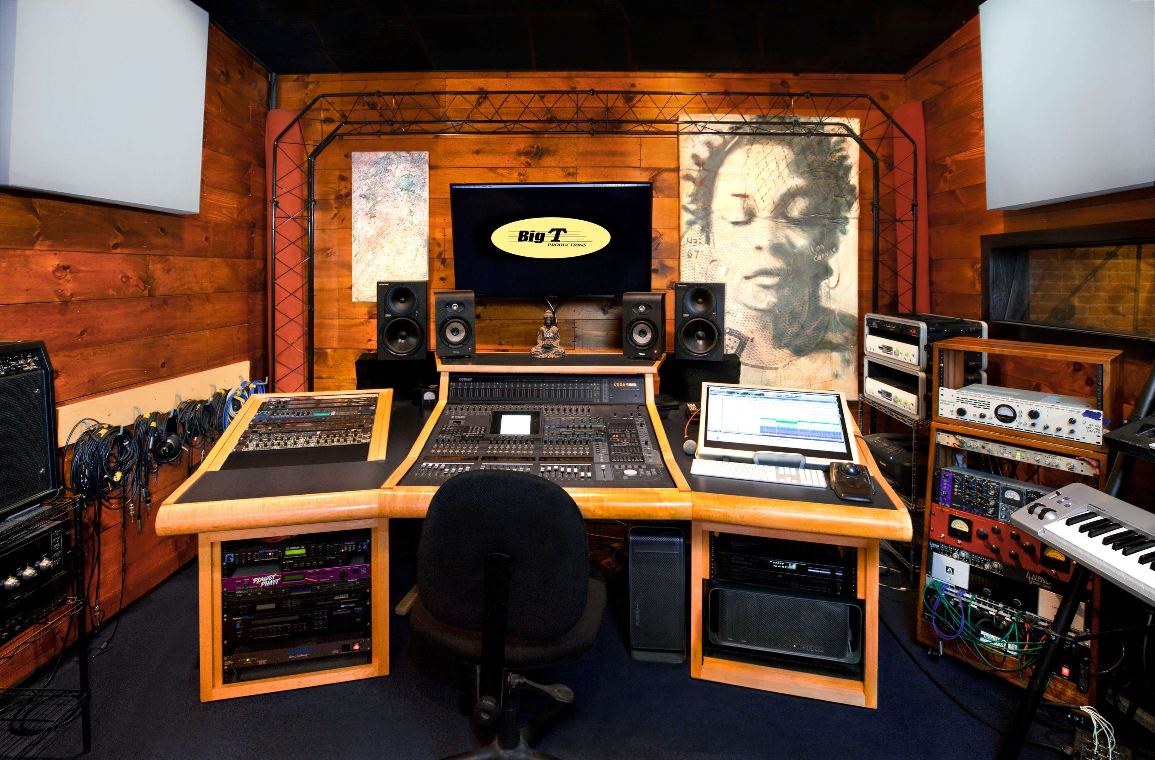 A music recording studio featuring a large mixing console, multiple speakers, and sound equipment arranged around a central workstation.