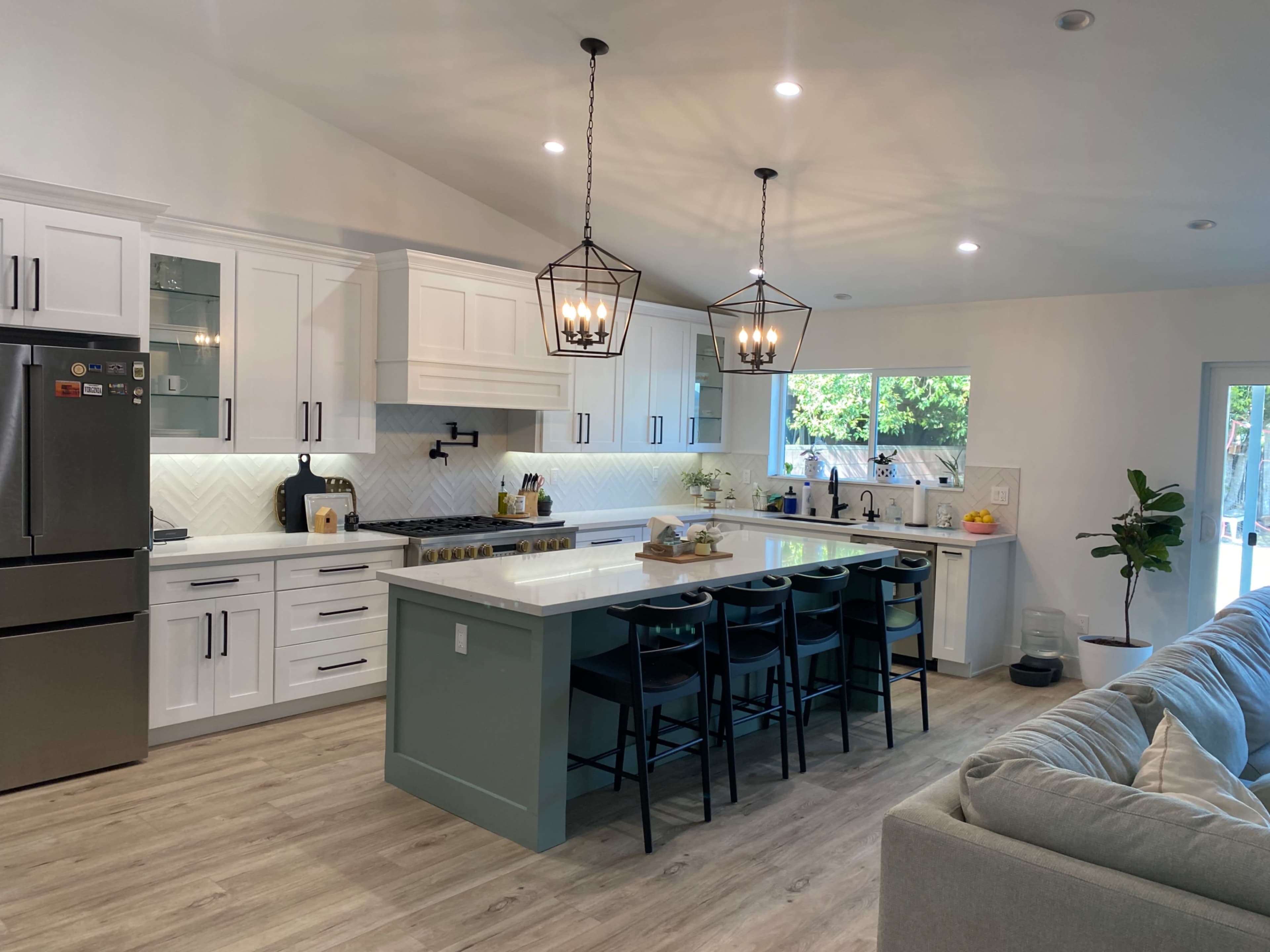 A modern kitchen features white cabinetry, a large island with seating for six, and stainless steel appliances.