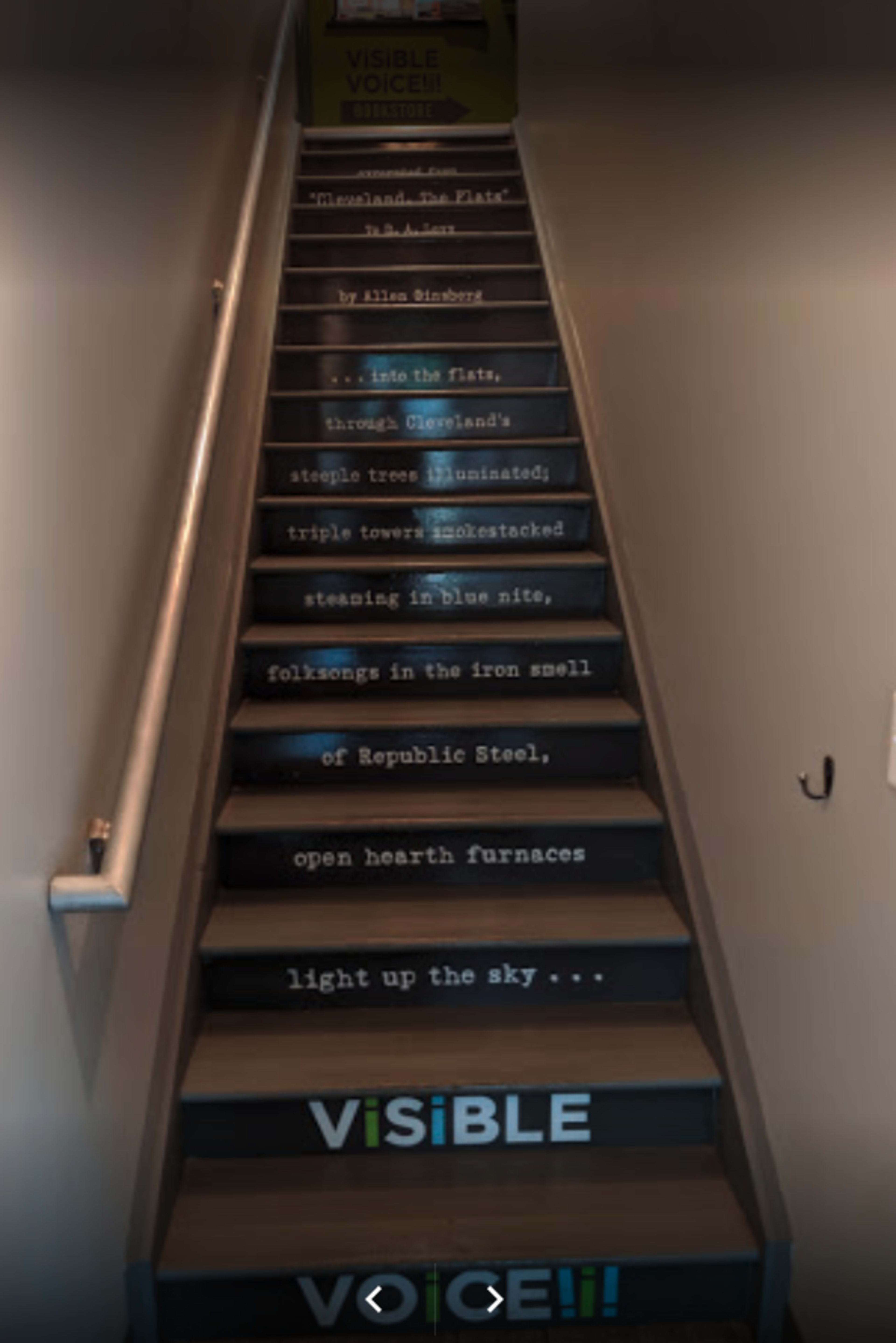 A staircase with text painted on each step, featuring lines related to themes of industrial heritage and community.