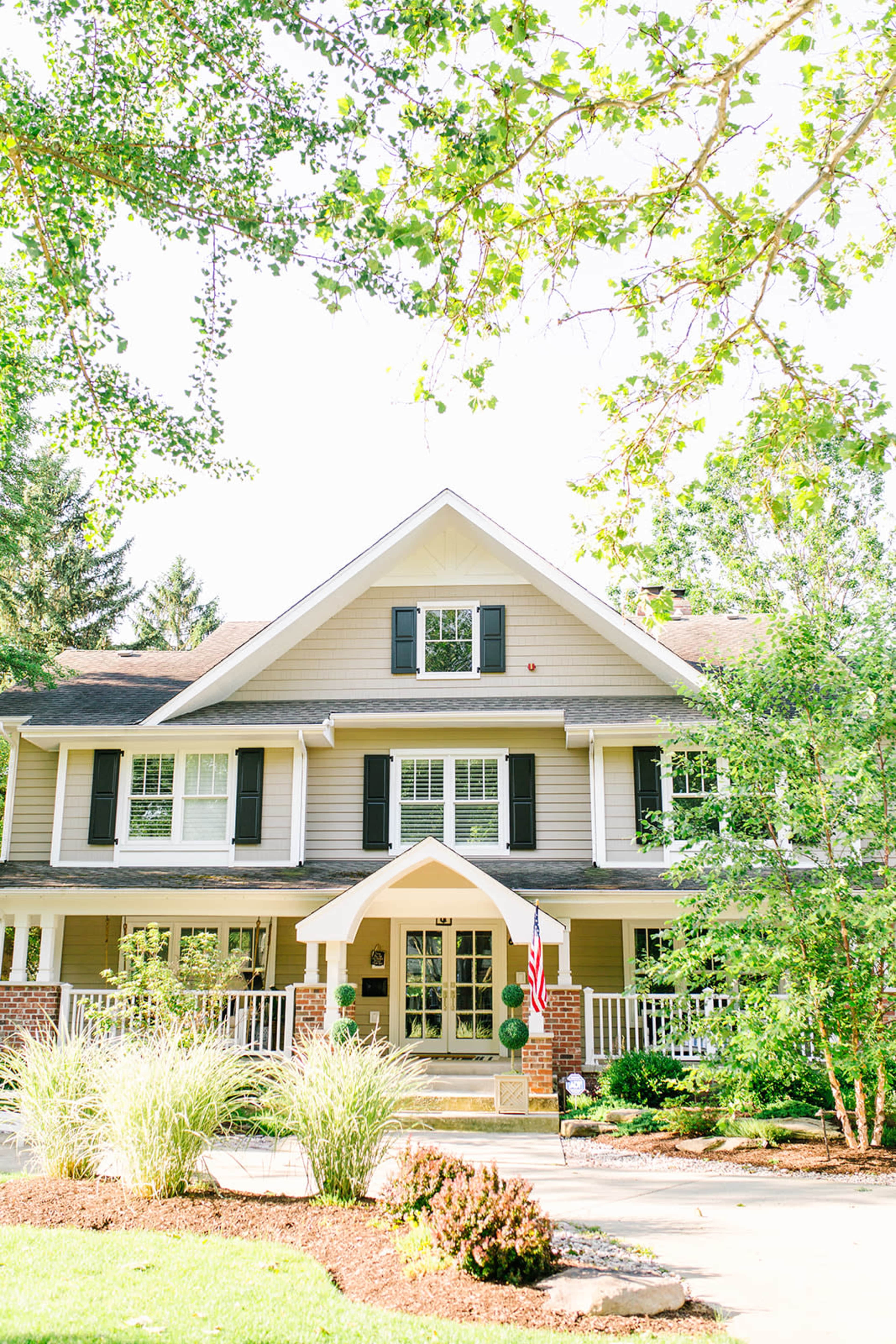 A two-story house with a peaked roof, front porch, and landscaped yard is visible in the image.