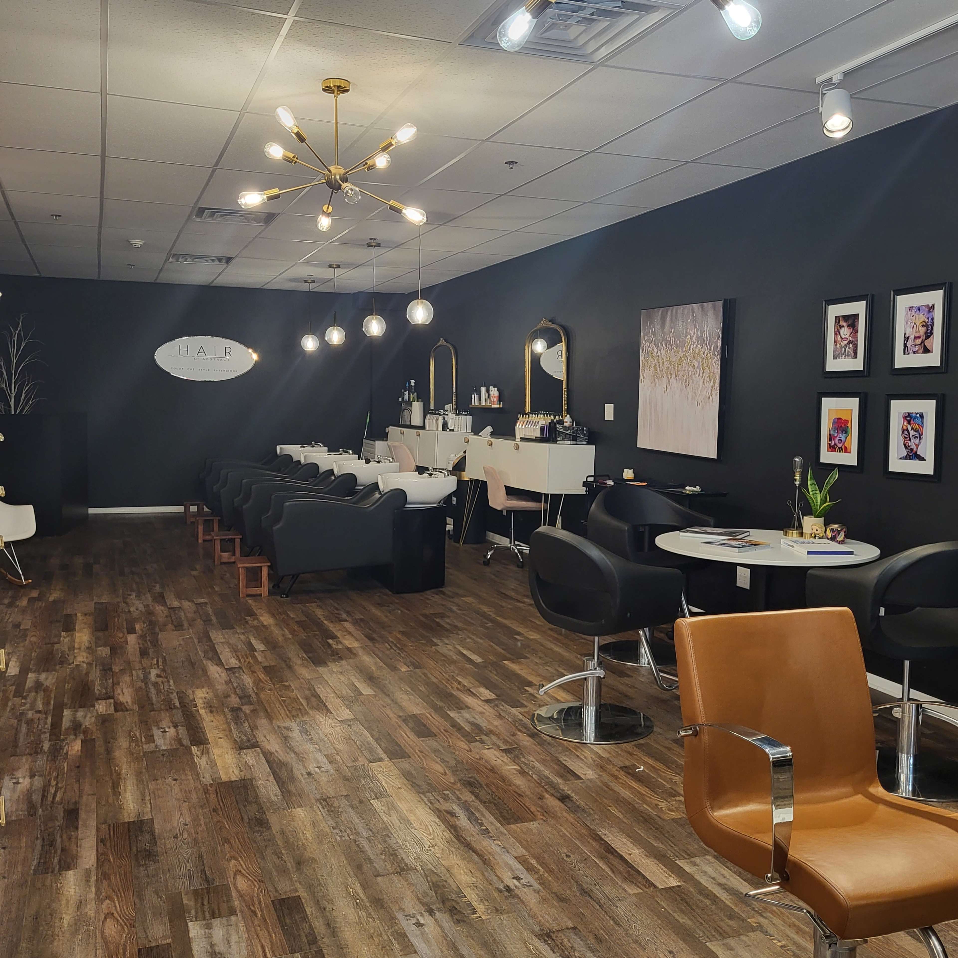 A modern hair salon with black walls, stylish furniture, and bright lighting.