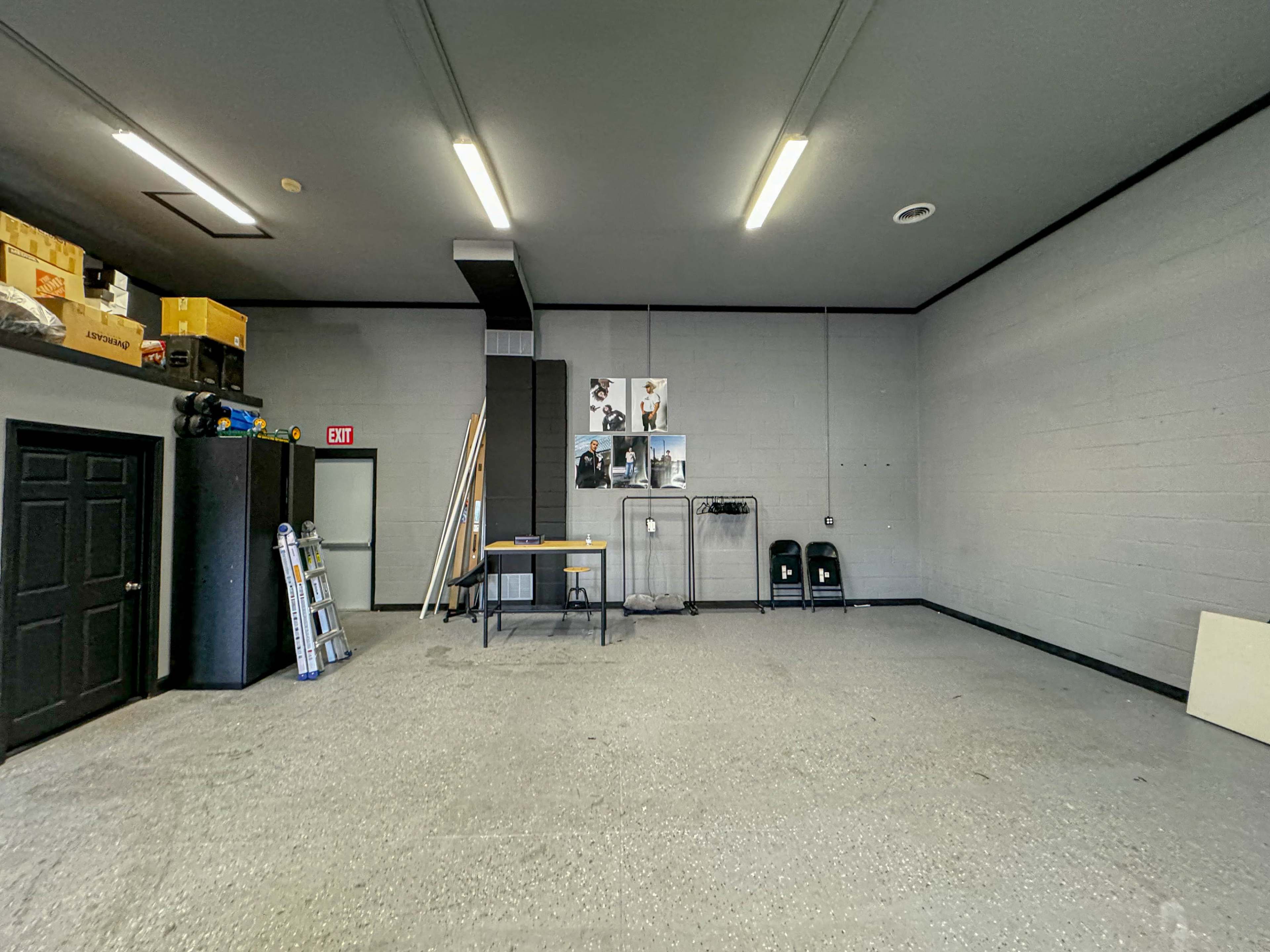 A spacious, empty garage with gray walls, a table in the center, and various storage items along the walls.