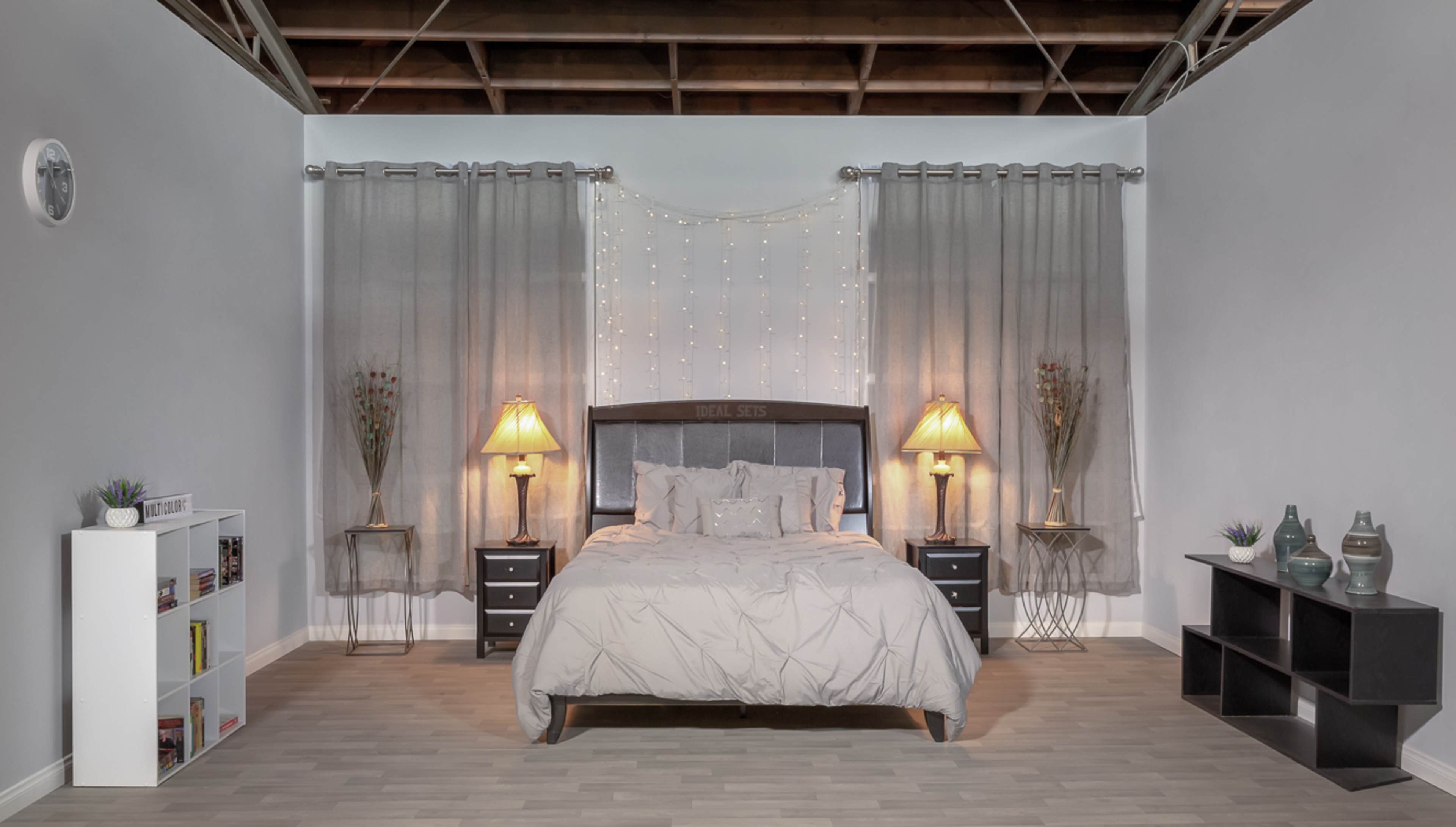 A neatly arranged bedroom with a large bed, two nightstands, lamps, and decorative curtains against a neutral-colored wall.