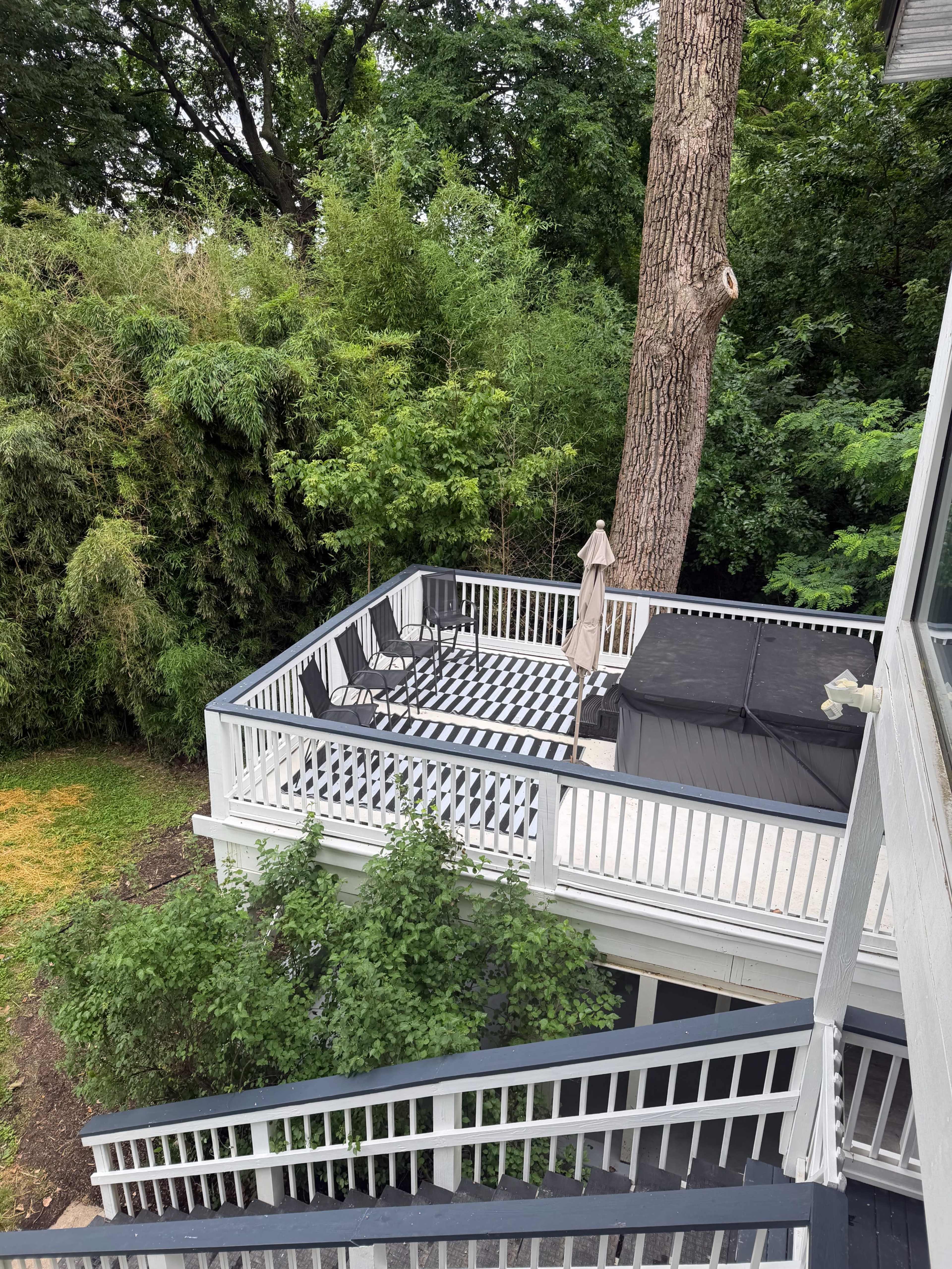The image shows a multi-level deck surrounded by greenery, including tall trees and shrubs.