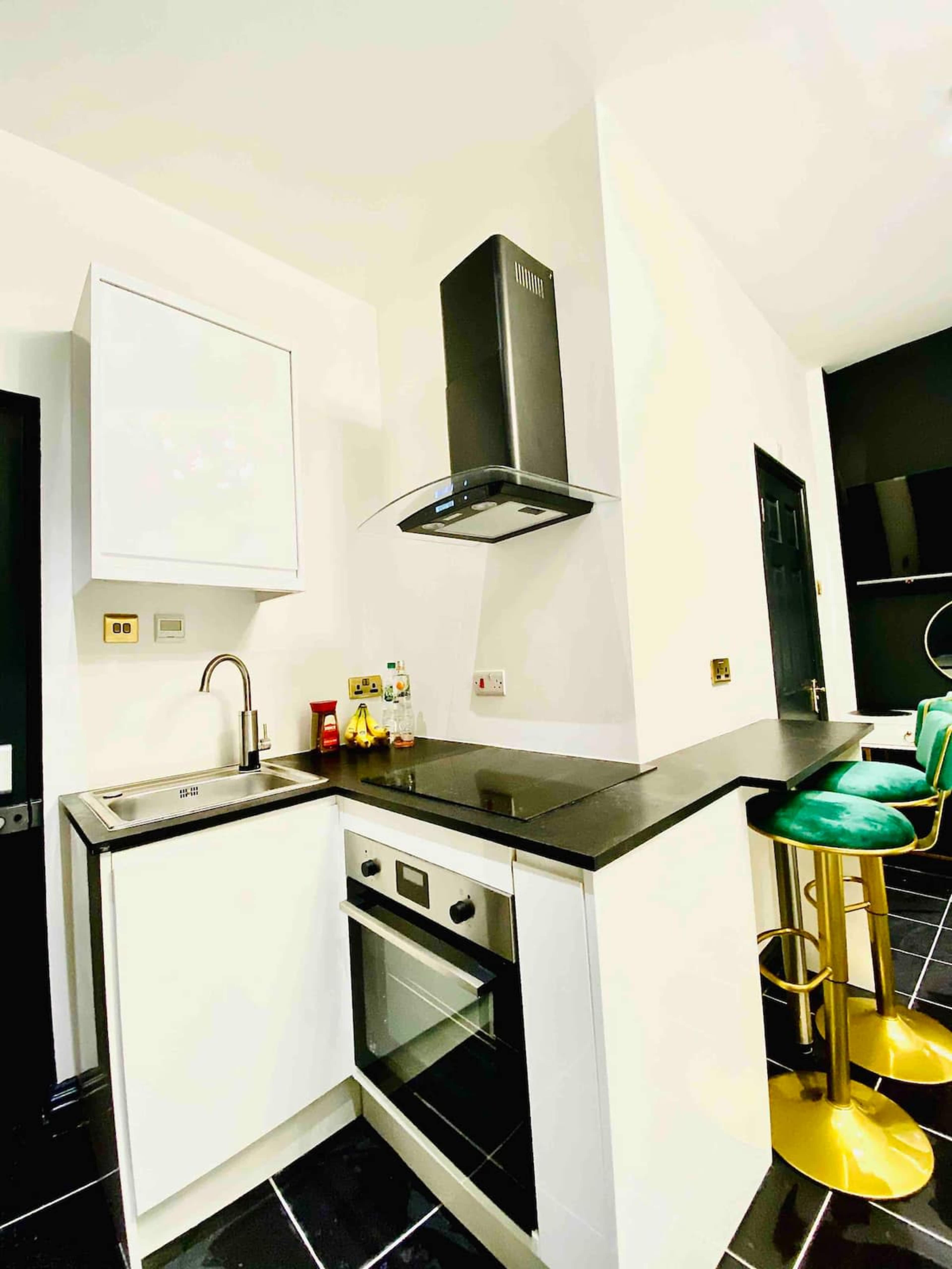 A modern kitchen with a black countertop, built-in oven, and a sleek range hood.
