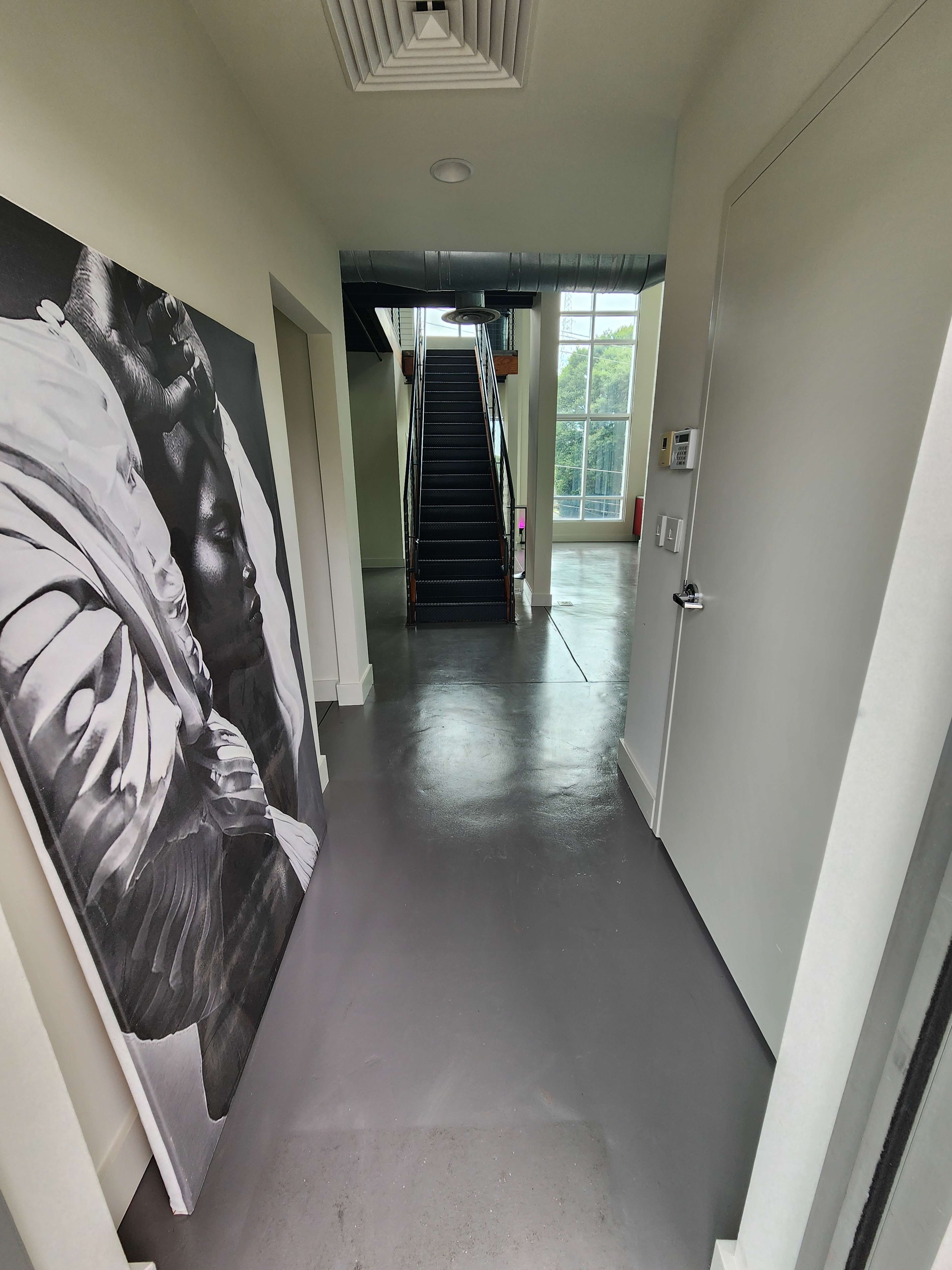 A hallway leading to a staircase, with a large black-and-white artwork displayed against one wall.