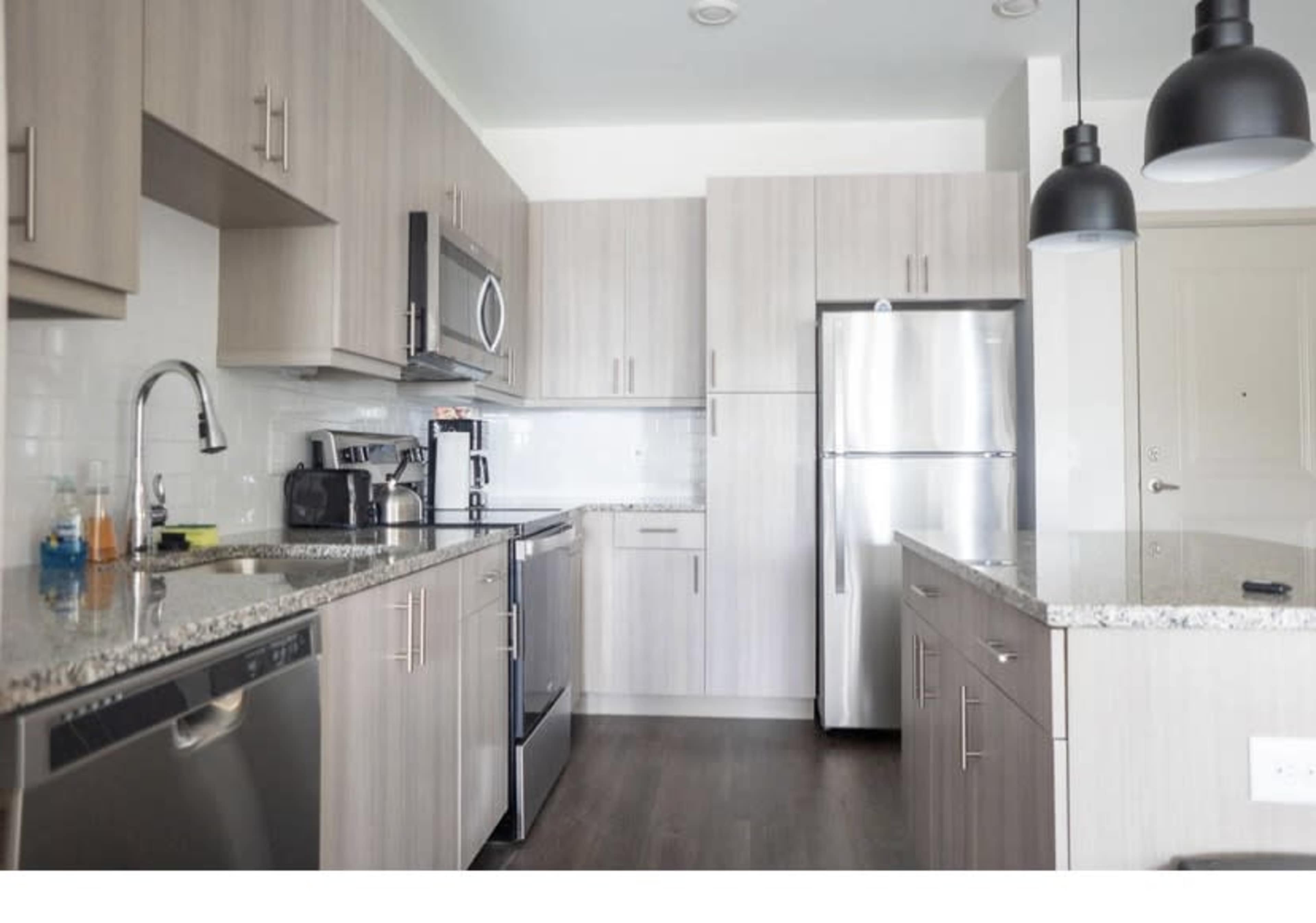 The kitchen features light wood cabinetry, stainless steel appliances, and a granite countertop with a modern design.