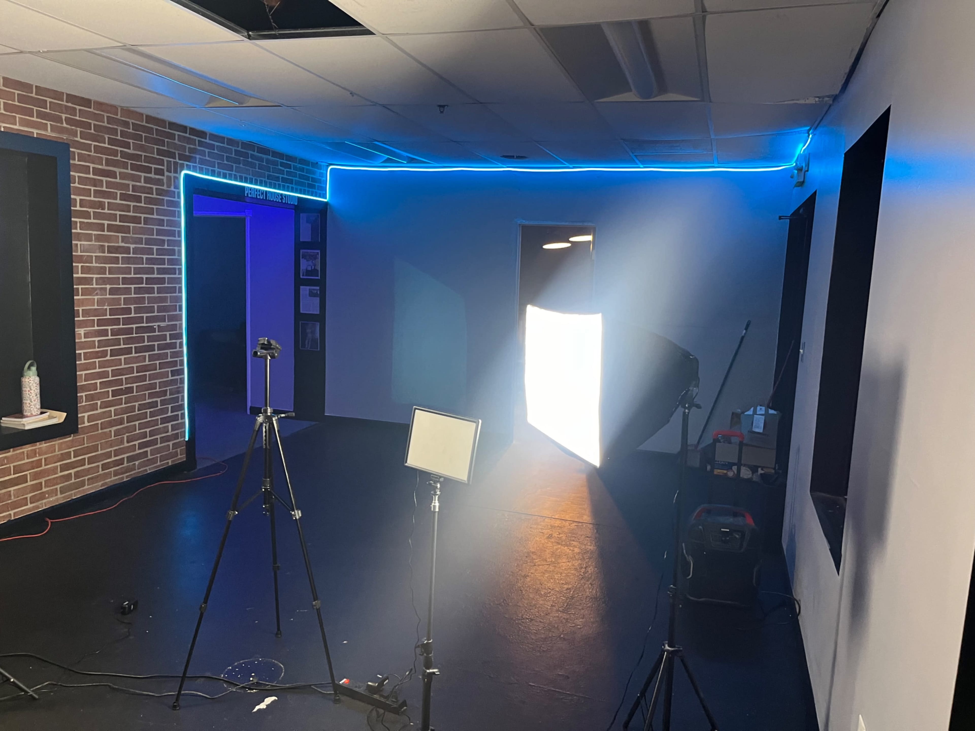 A studio space with lighting equipment and a bright light source illuminating one corner, while blue LED lights outline the walls.