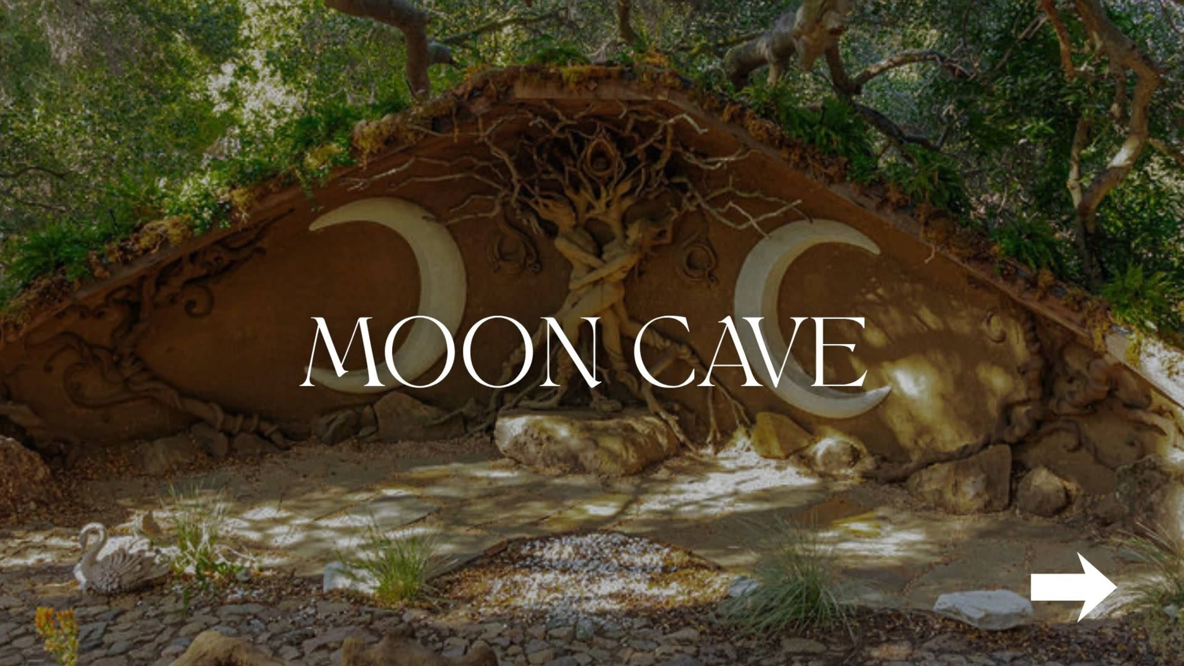 The image shows a cave structure adorned with crescent moon designs and surrounded by natural vegetation.