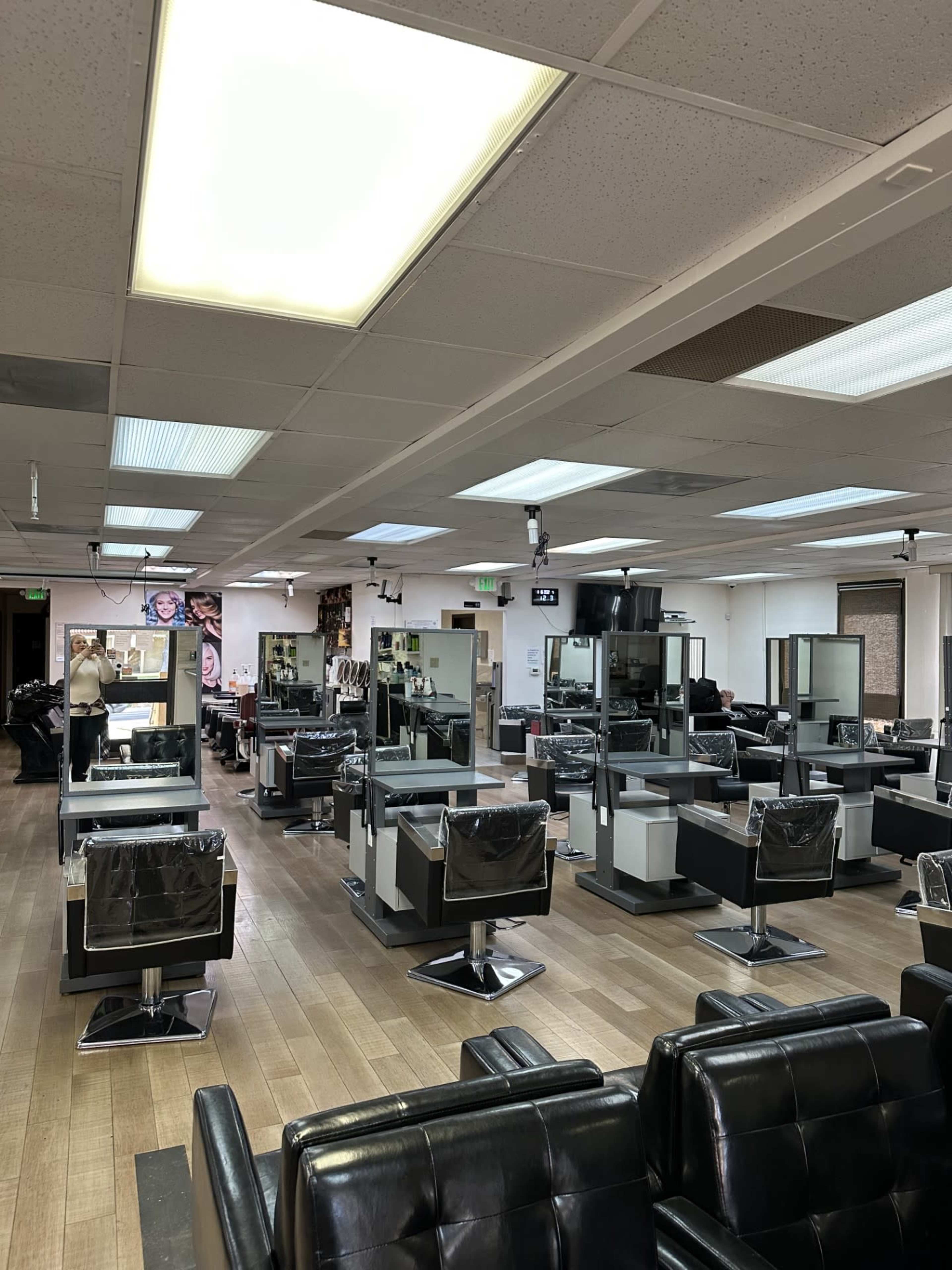 A spacious hair salon with multiple styling stations, each equipped with mirrors and black salon chairs.