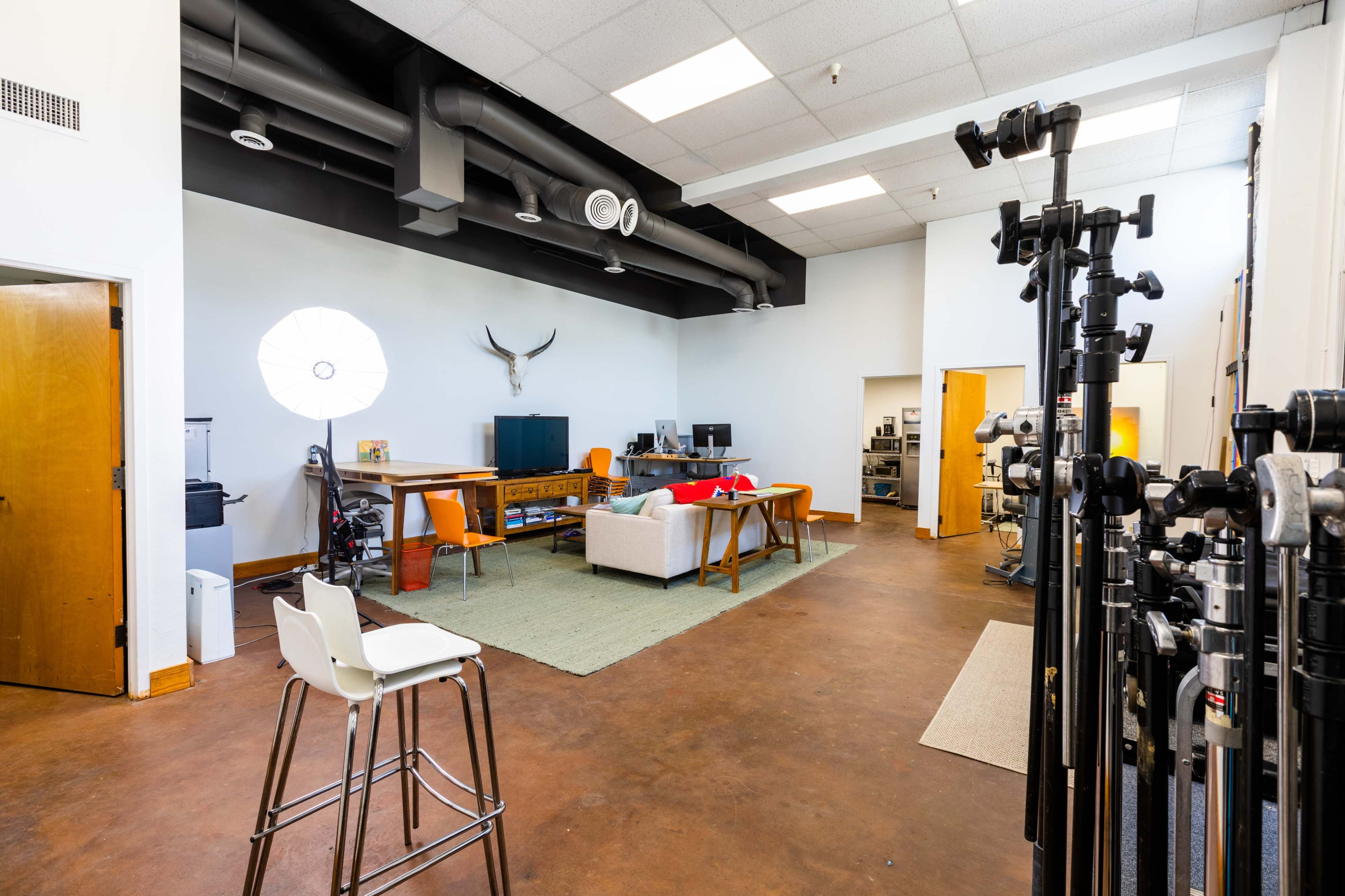 A spacious studio with a seating area, computer workstations, and various photography equipment along one side.