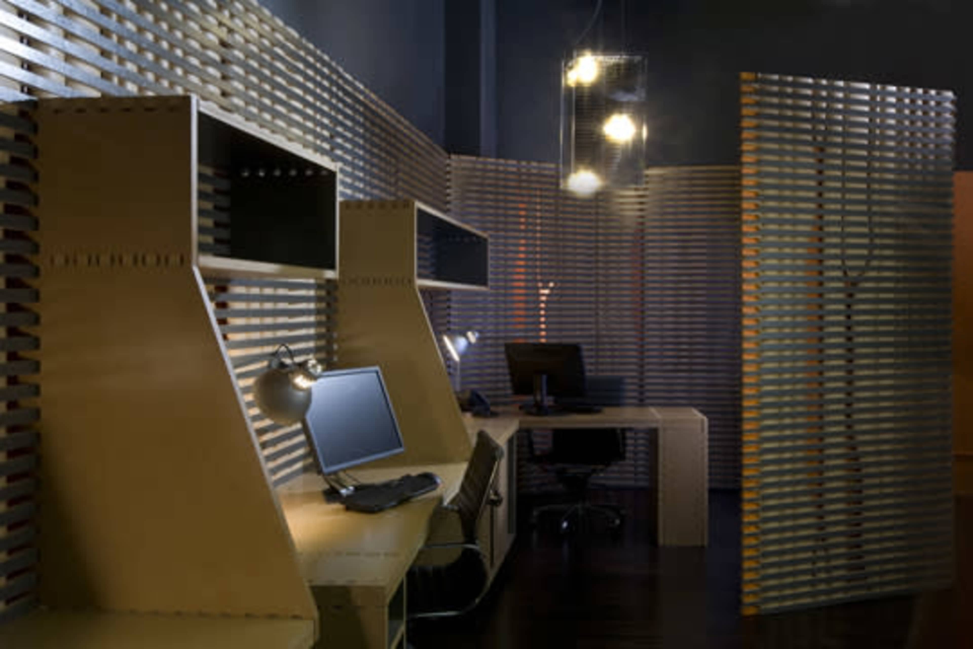 A modern office space with wooden partitions, a desk with a computer, and dim lighting.