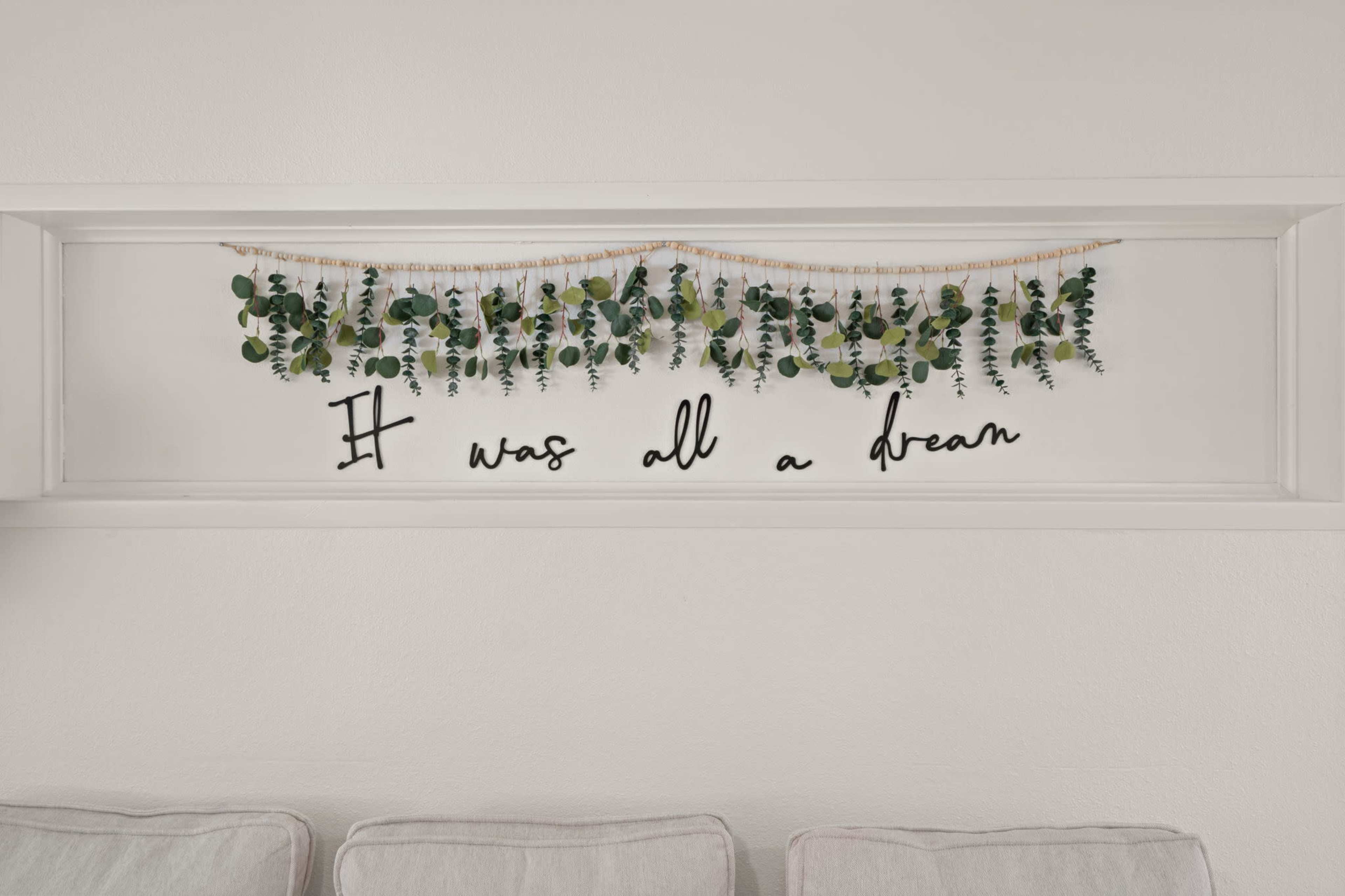 A decorative wall display features artificial greenery with the phrase "It was all a dream" beneath it.