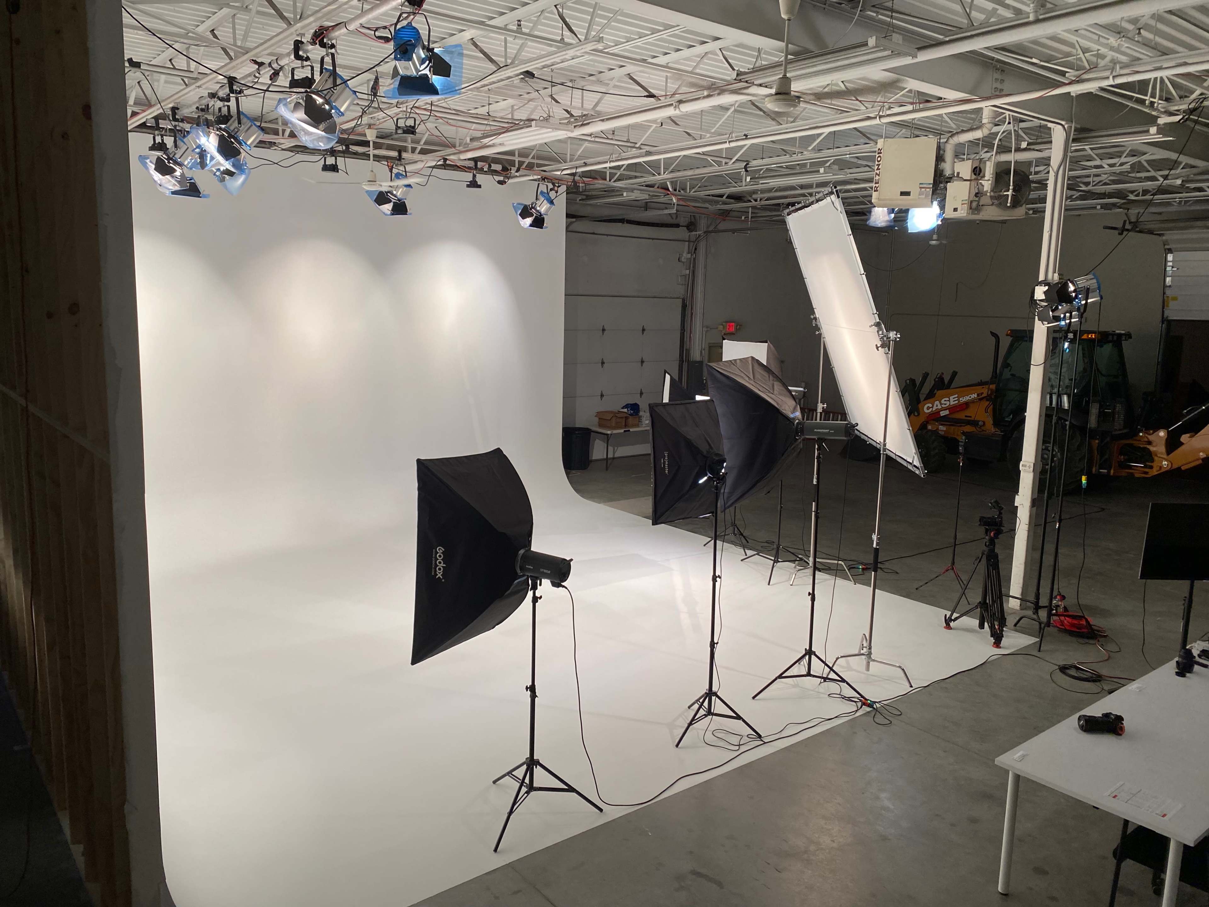 A photography studio equipped with multiple lighting setups aiming at a white backdrop.