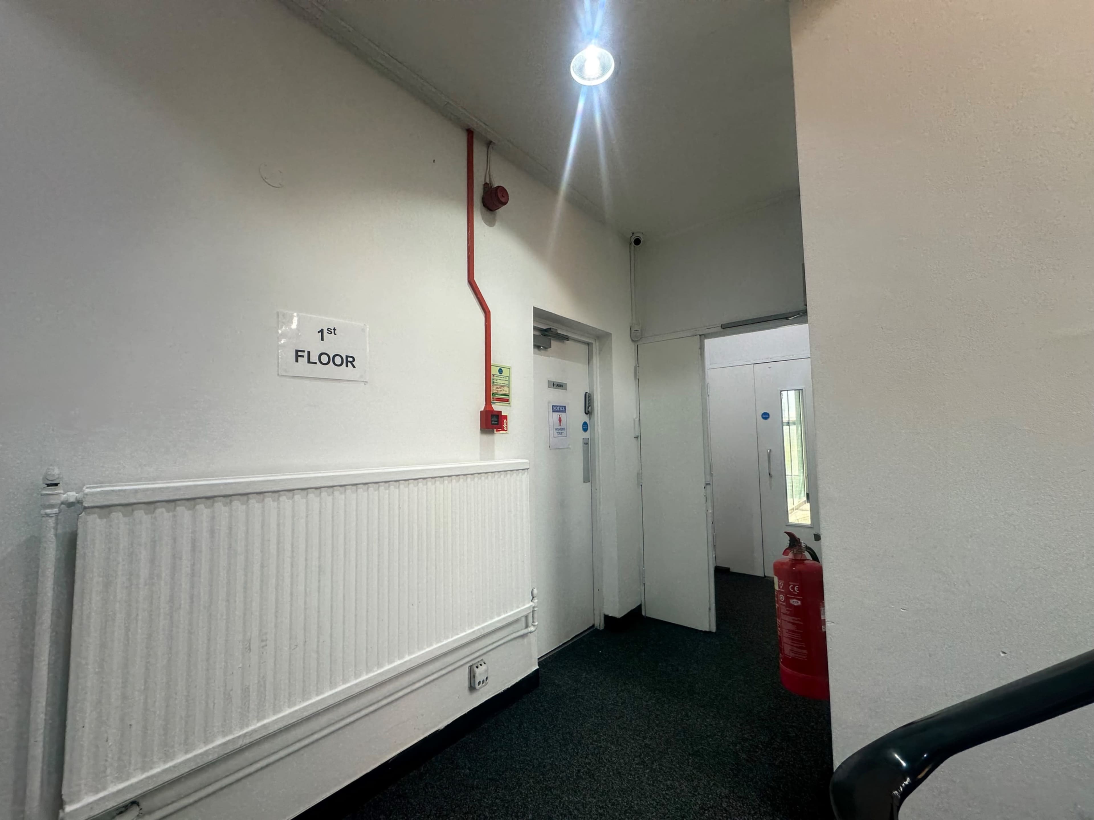 The image shows a hallway on the first floor with a fire extinguisher, doors, and a sign indicating "1st FLOOR."