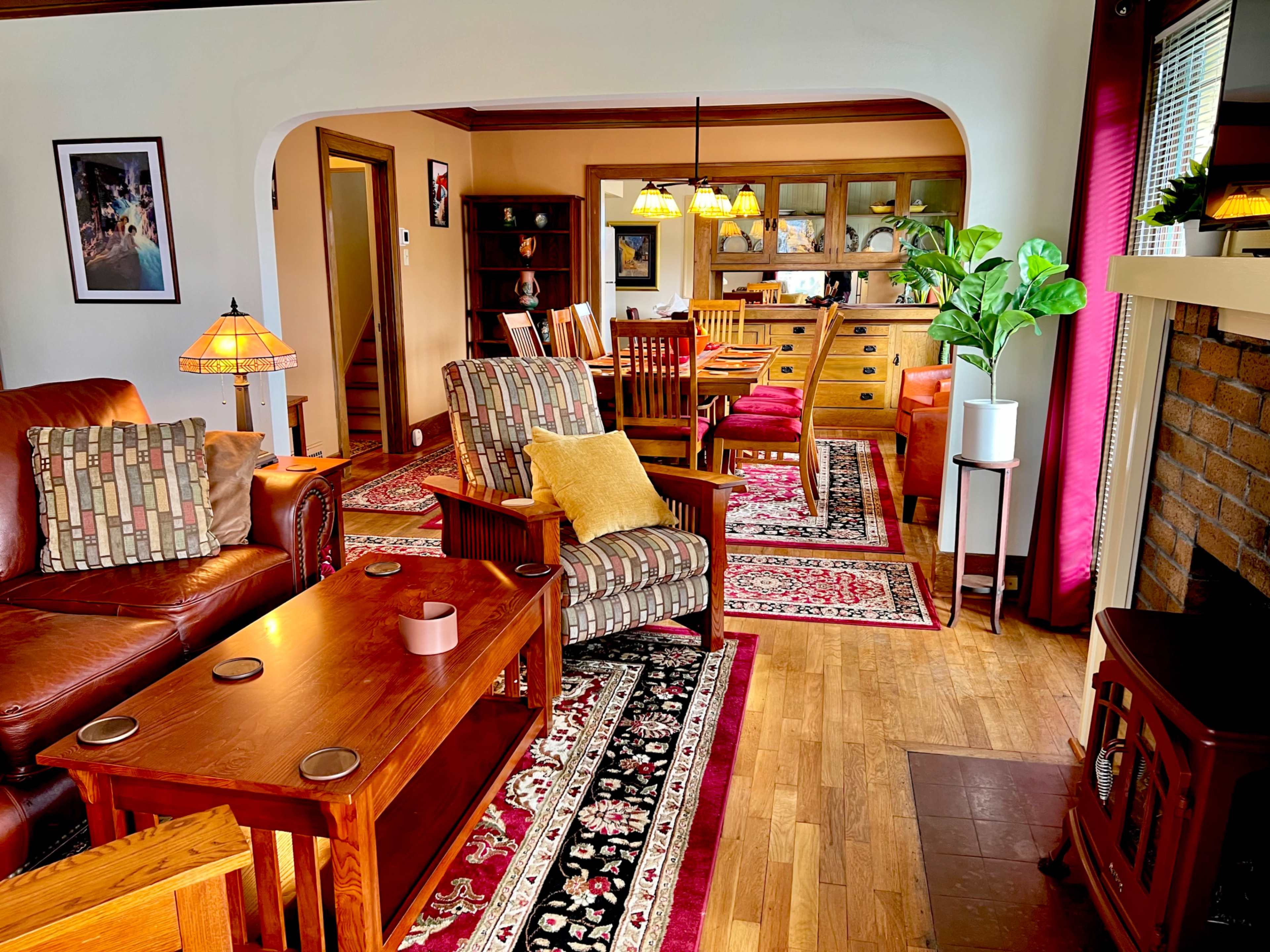 A cozy living room and dining area with wooden furniture, floral rugs, and a fireplace.