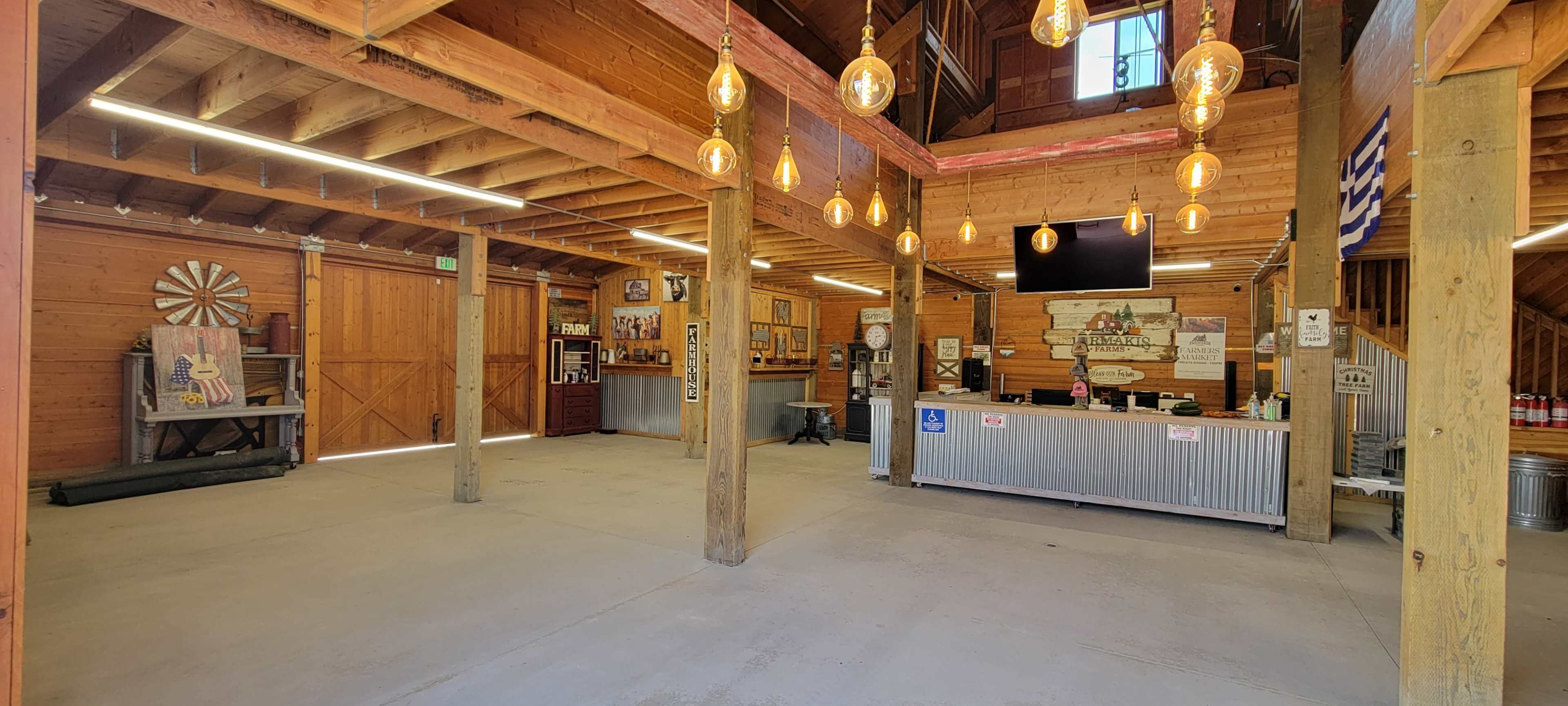 An empty rustic interior of a wooden building with exposed beams, pendant lighting, and a service counter.