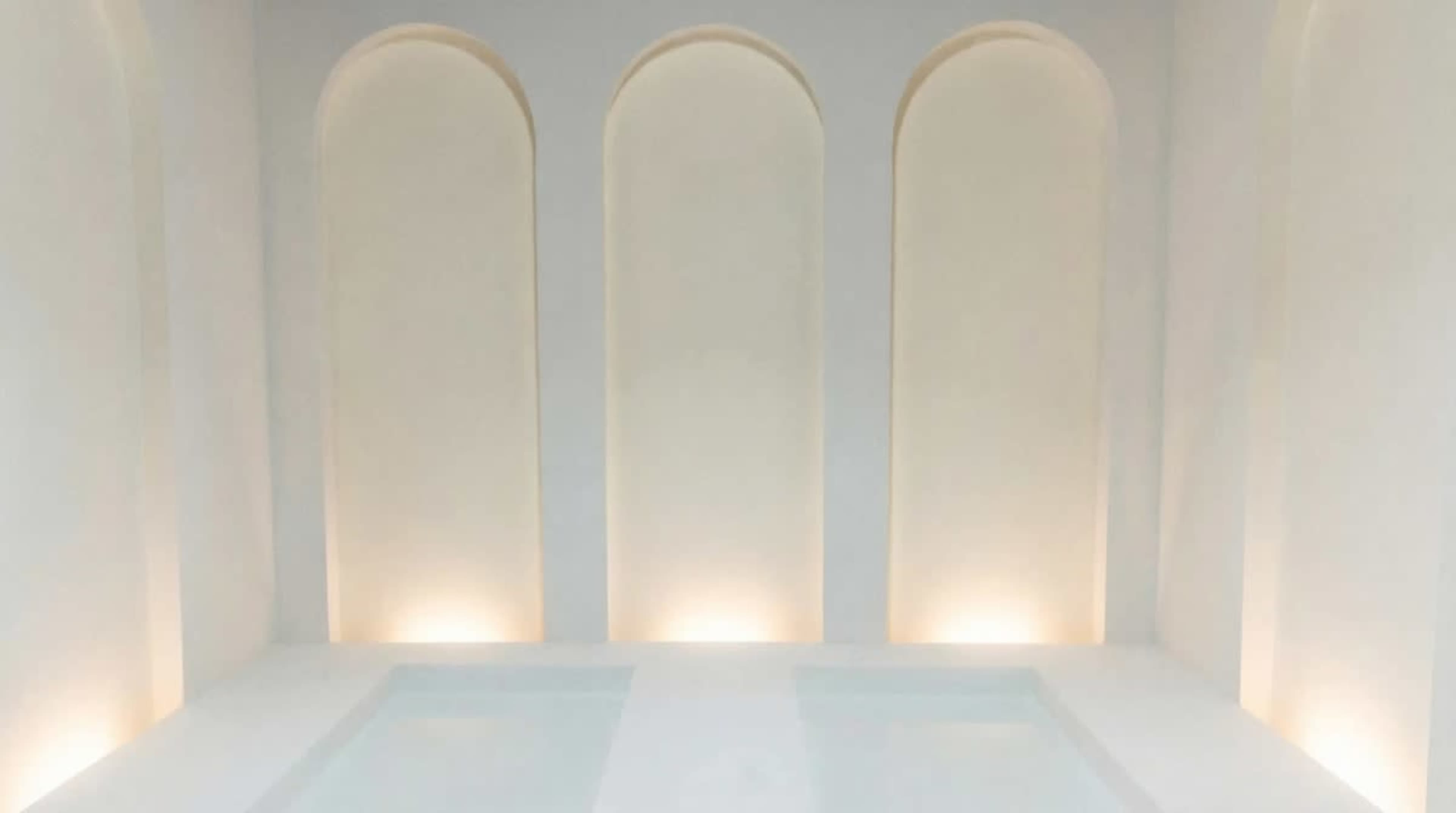 The image depicts a minimalist spa-like interior featuring three arched niches illuminated subtly against a light-colored wall.