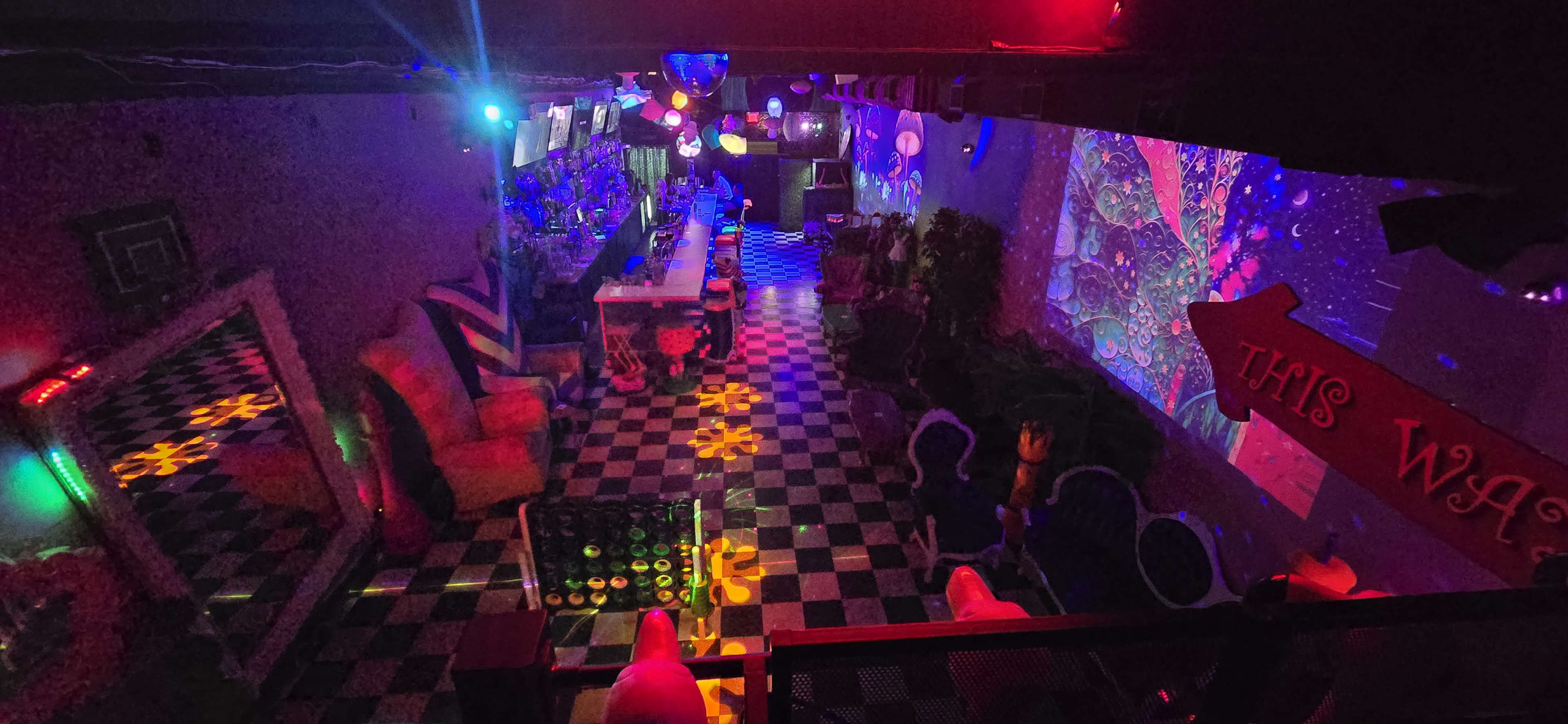 A vibrant, colorful lounge area with patterned flooring, bar seating, and artistic projections on the wall.