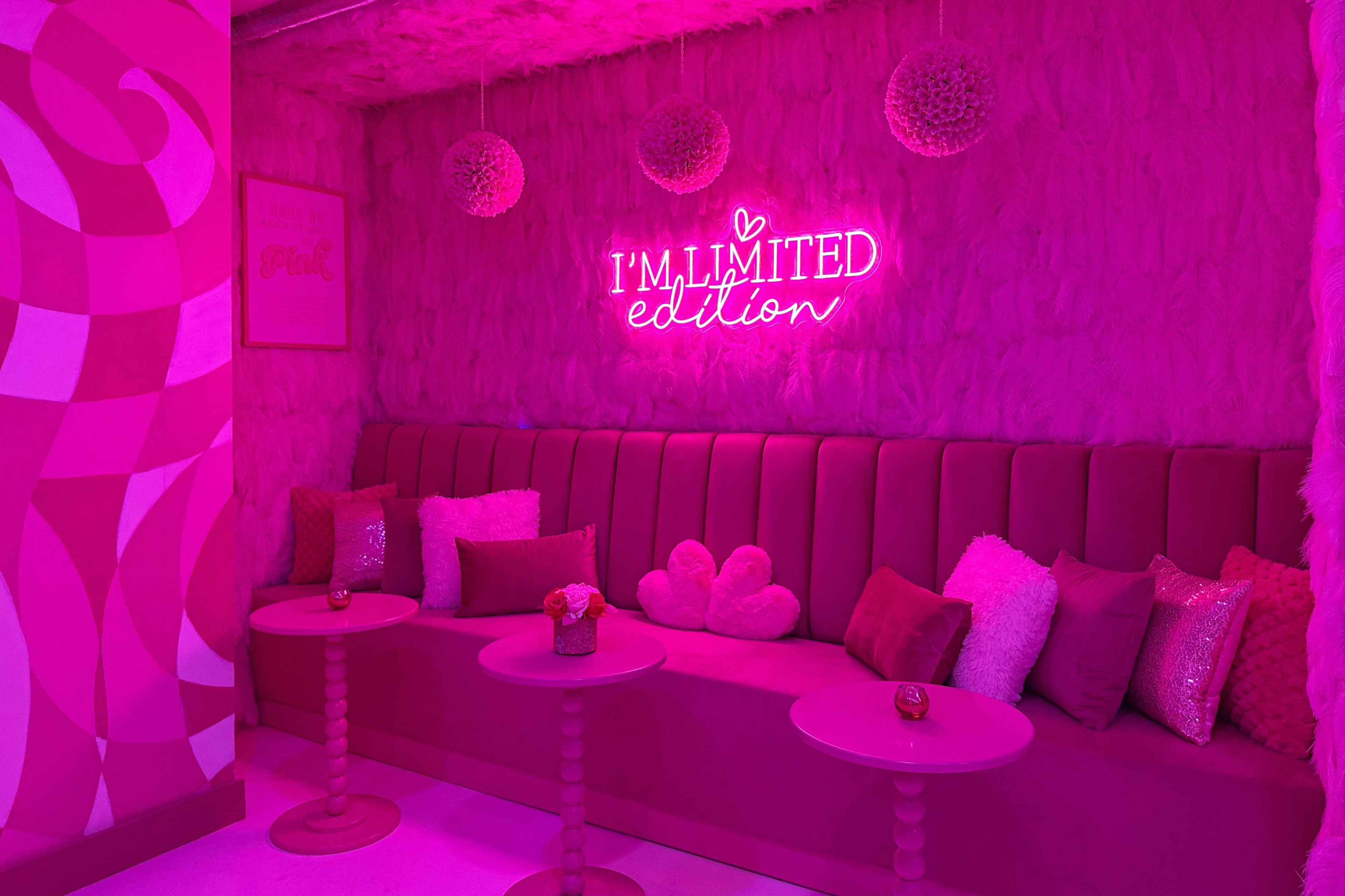 The scene features a pink-themed lounge area with a plush seating arrangement, circular tables, and a neon sign that reads "I'M LIMITED edition."