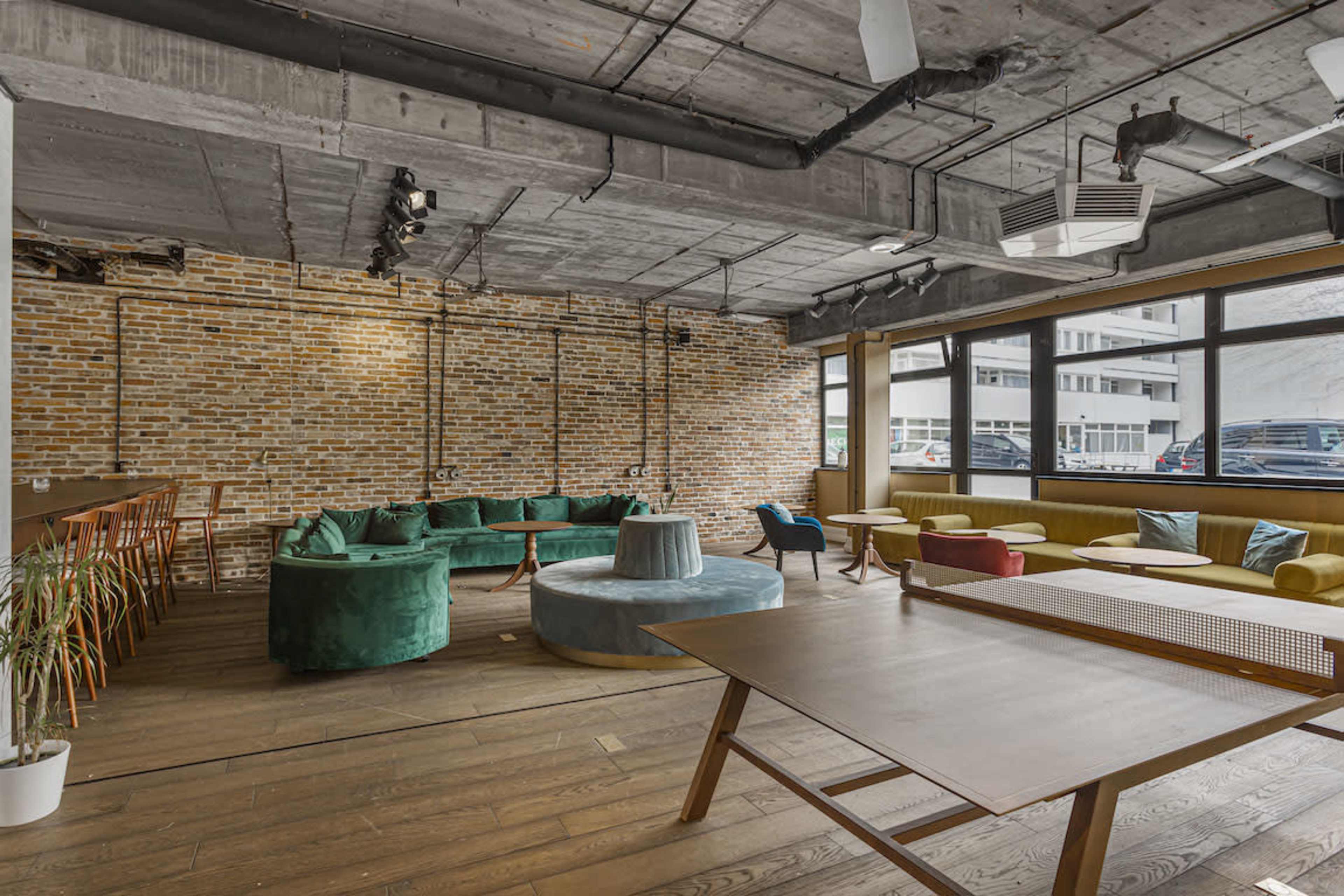 A modern, spacious café with brick walls, a mix of seating arrangements, and large windows providing natural light.