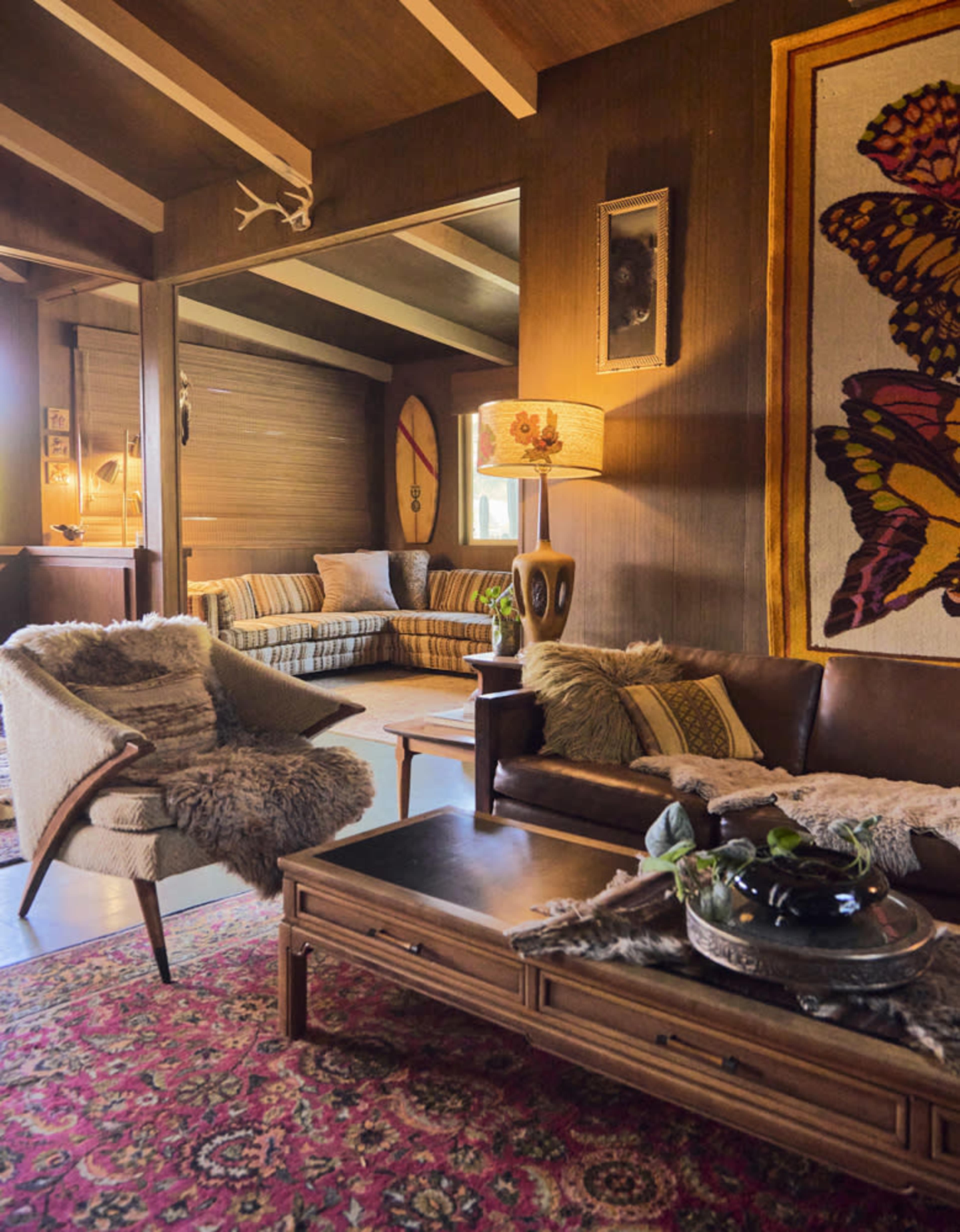 A cozy living room featuring a brown leather sofa, a small wooden coffee table, and a patterned rug, with a lamp and decorative items adding to the interior design.