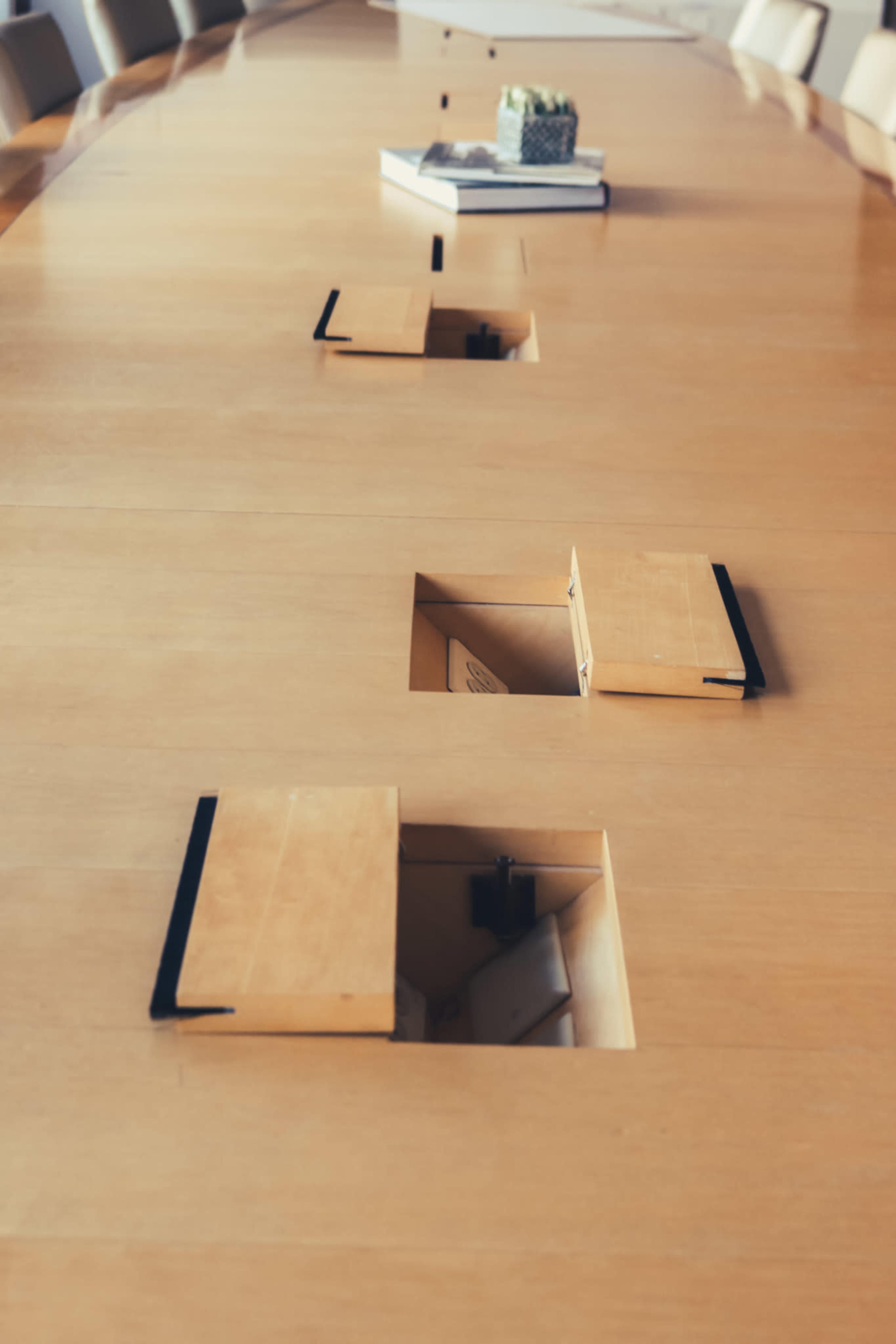 A wooden conference table with several rectangular openings for cable management and materials.