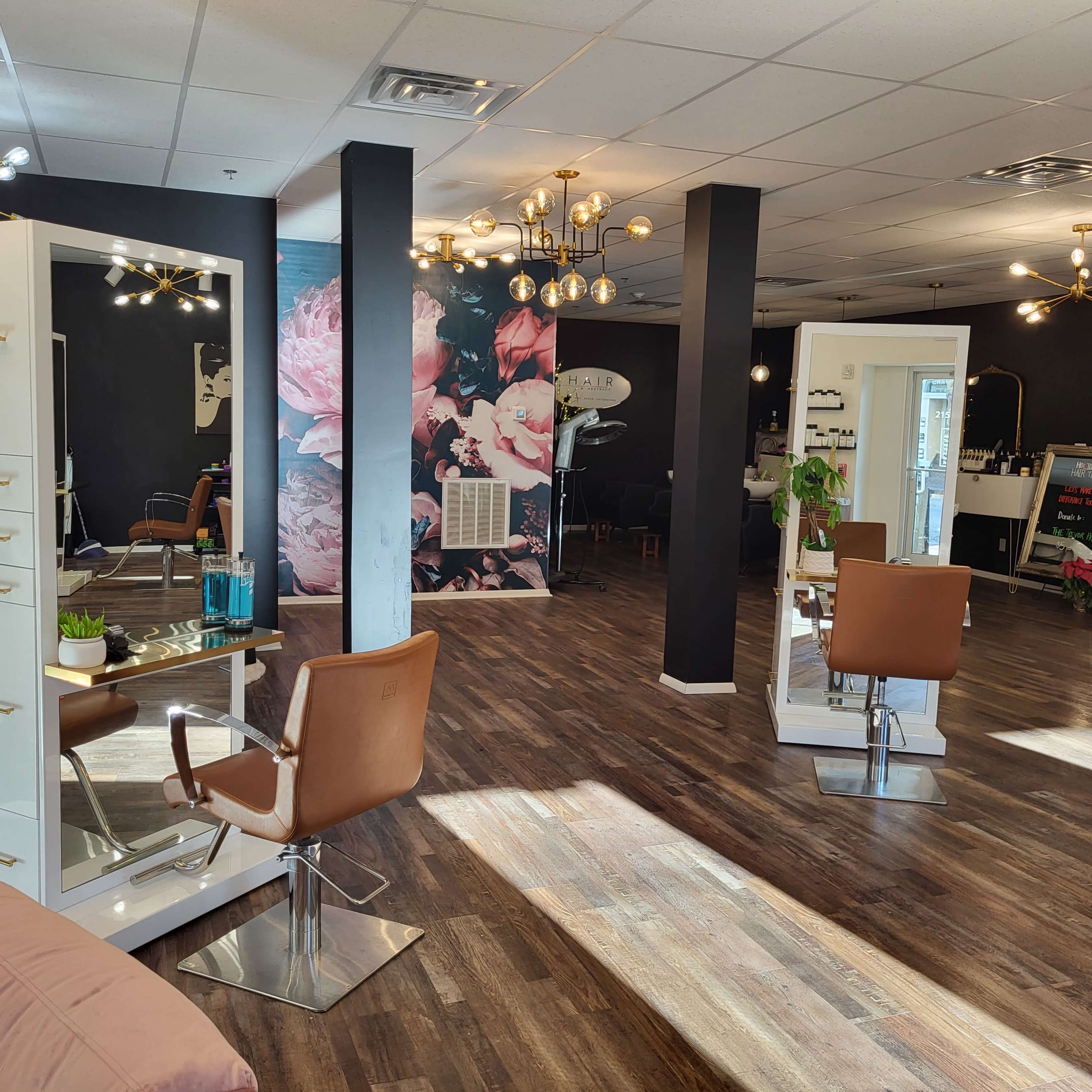 A modern hair salon with two styling stations, a floral mural on the wall, and a mix of lighting fixtures.