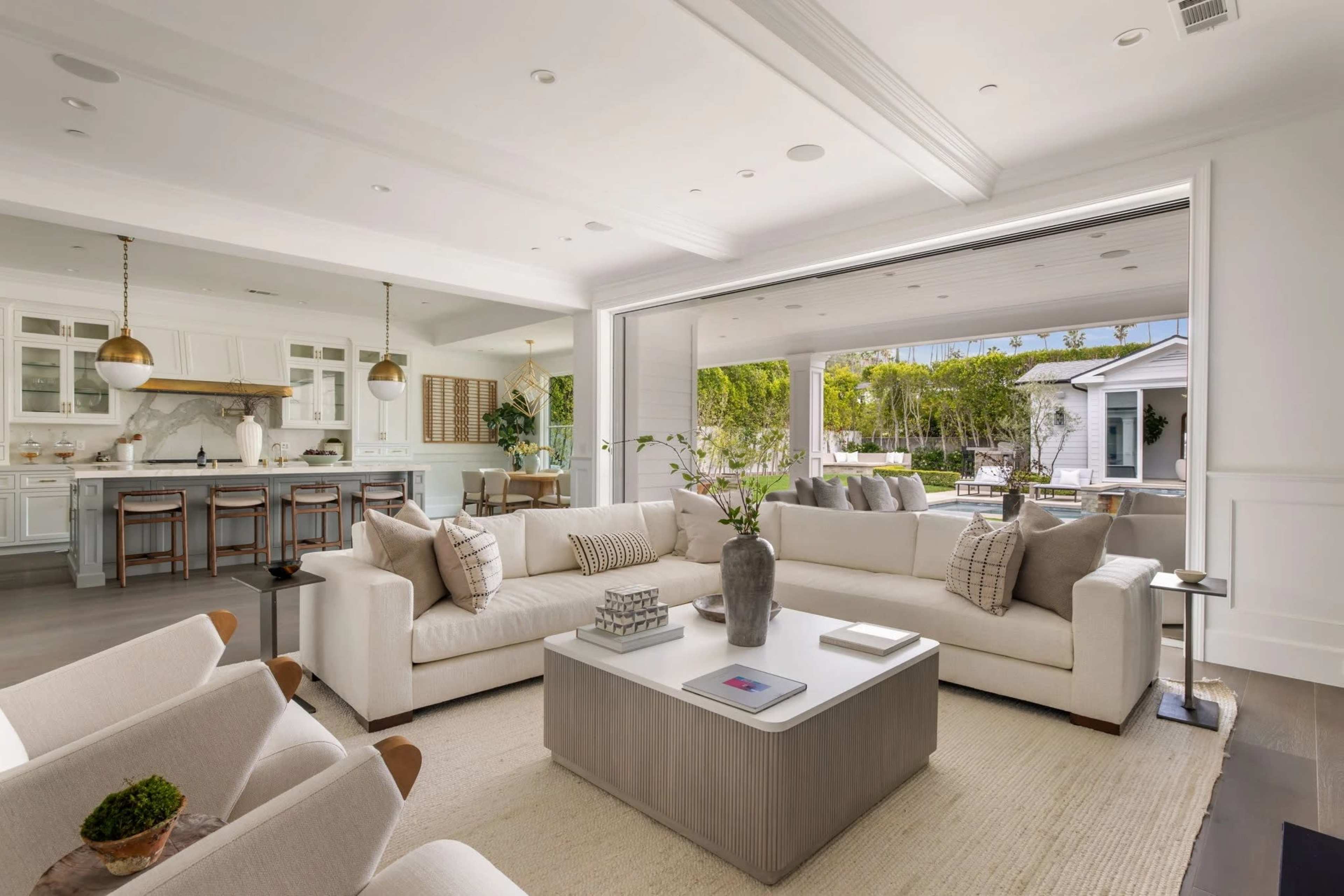 A spacious living room features a large sectional sofa, a coffee table, and a view of an outdoor patio through sliding glass doors.